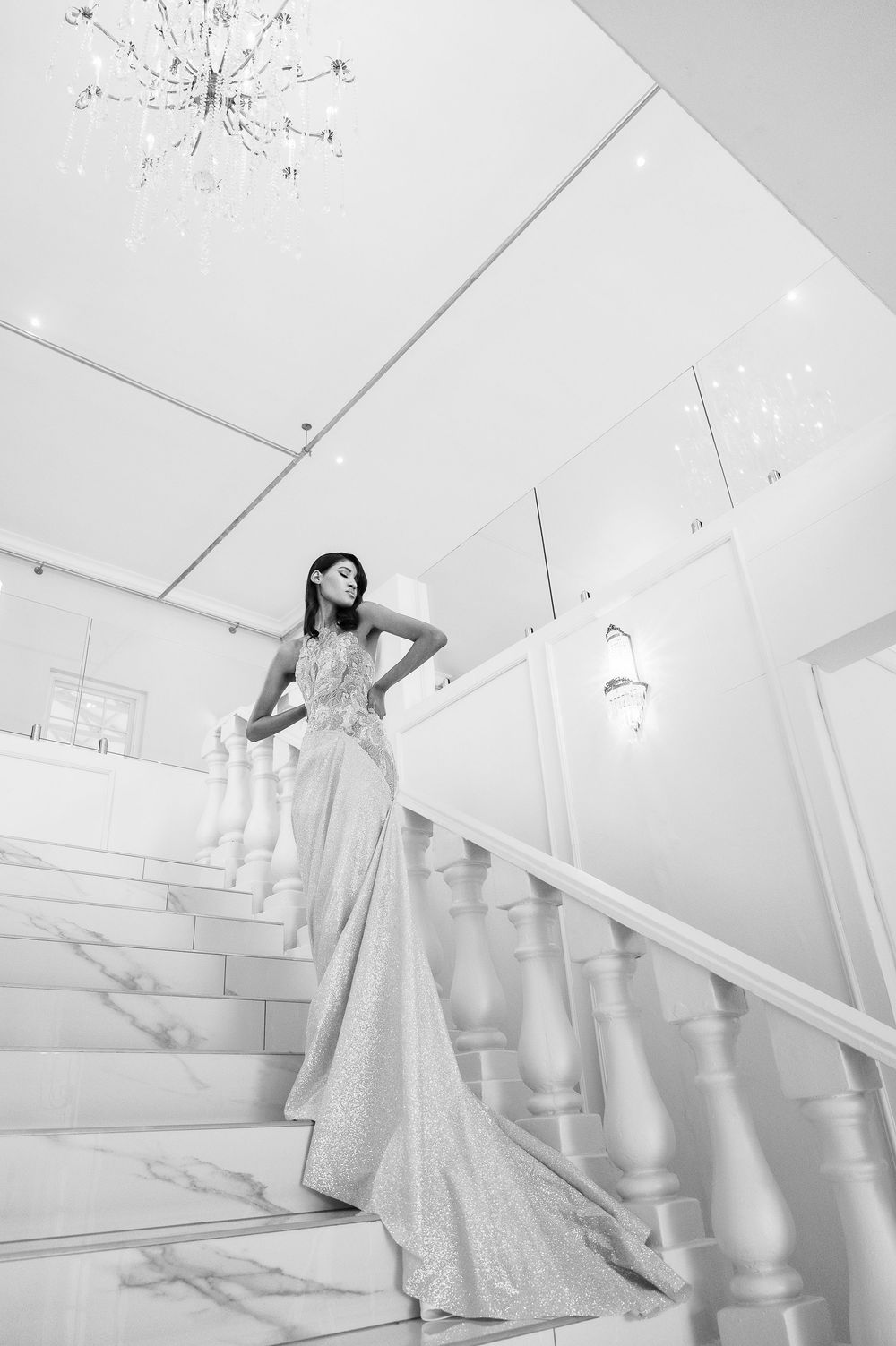A dramatic bridal portrait series showing flowing white gown on elegant staircase with white railings.