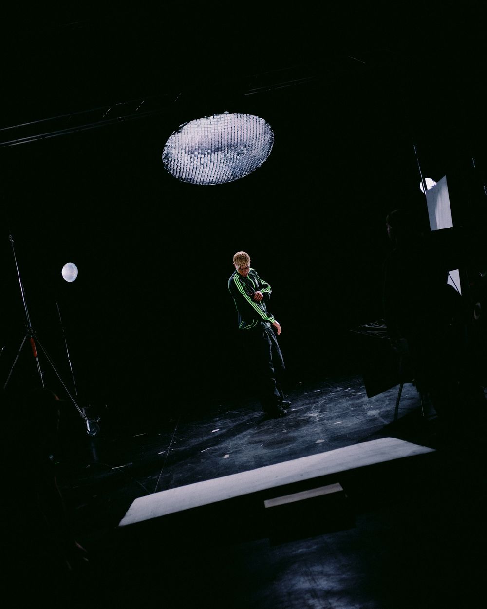 A person performs a dramatic aerial dance move suspended from ropes against a dark background on stage.