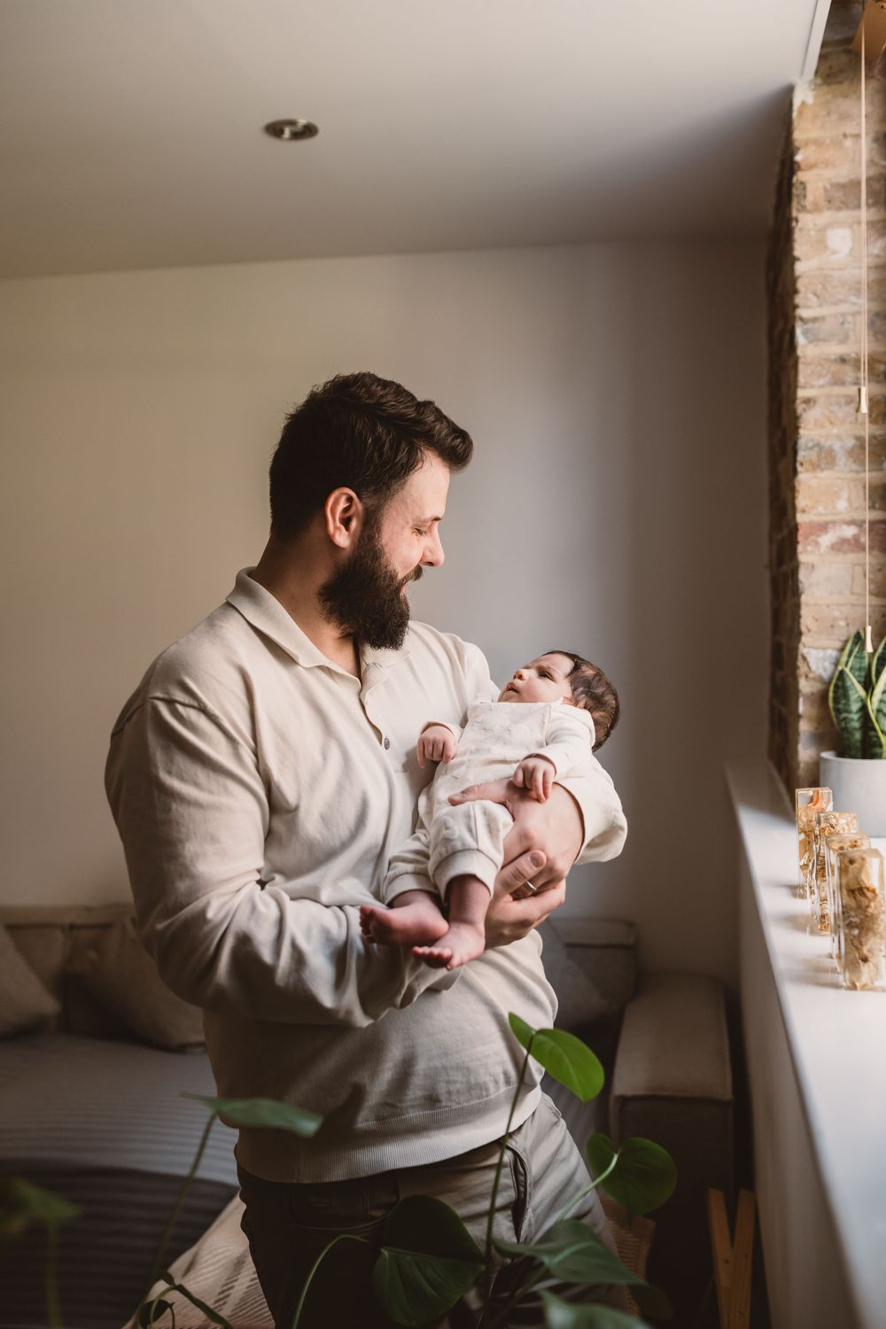 A heartwarming interaction between a father in white clothing and a baby in a bright room.