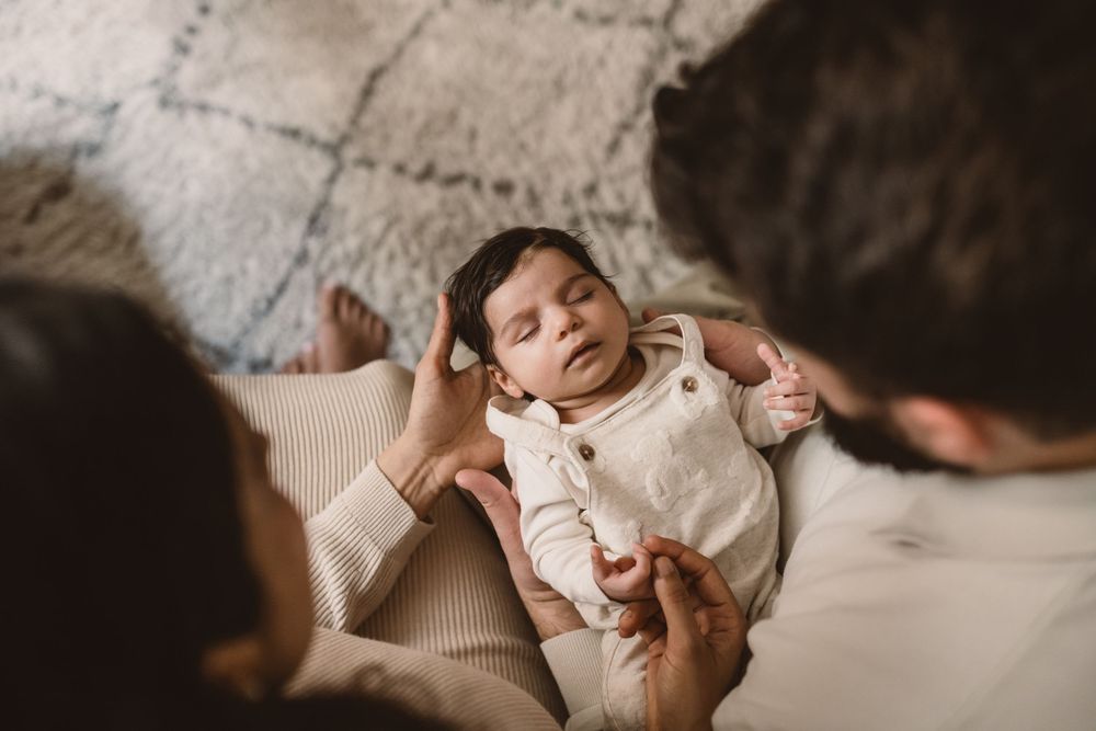 A sleeping baby lying on her parents' arms.
