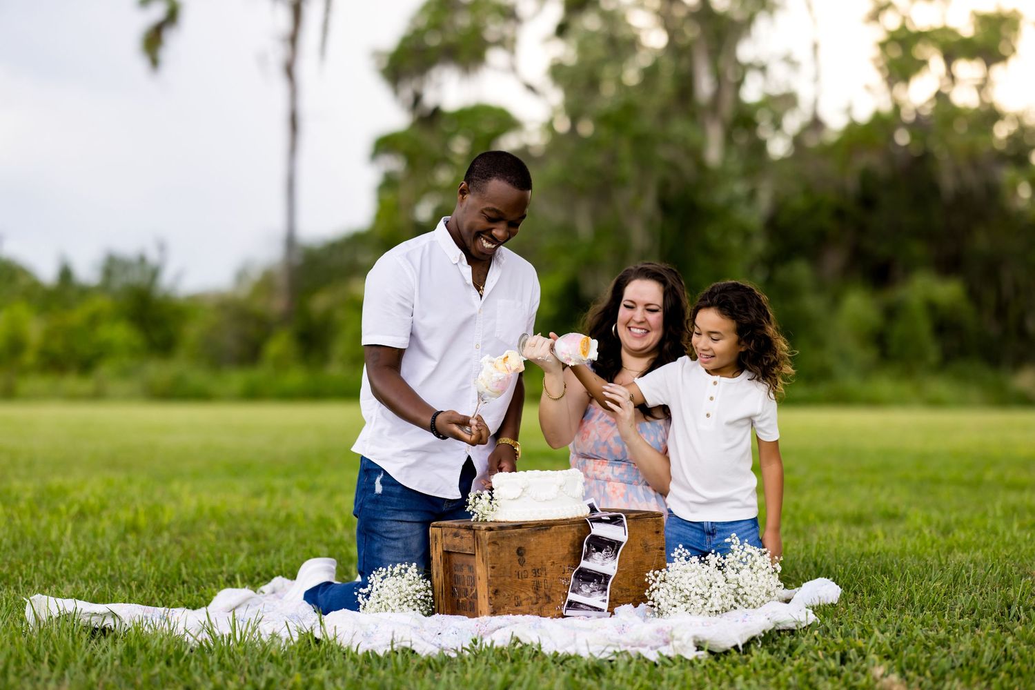 A family enjoys a picnic on a blanket in a grassy field with food, drinks and genuine moments of connection together.