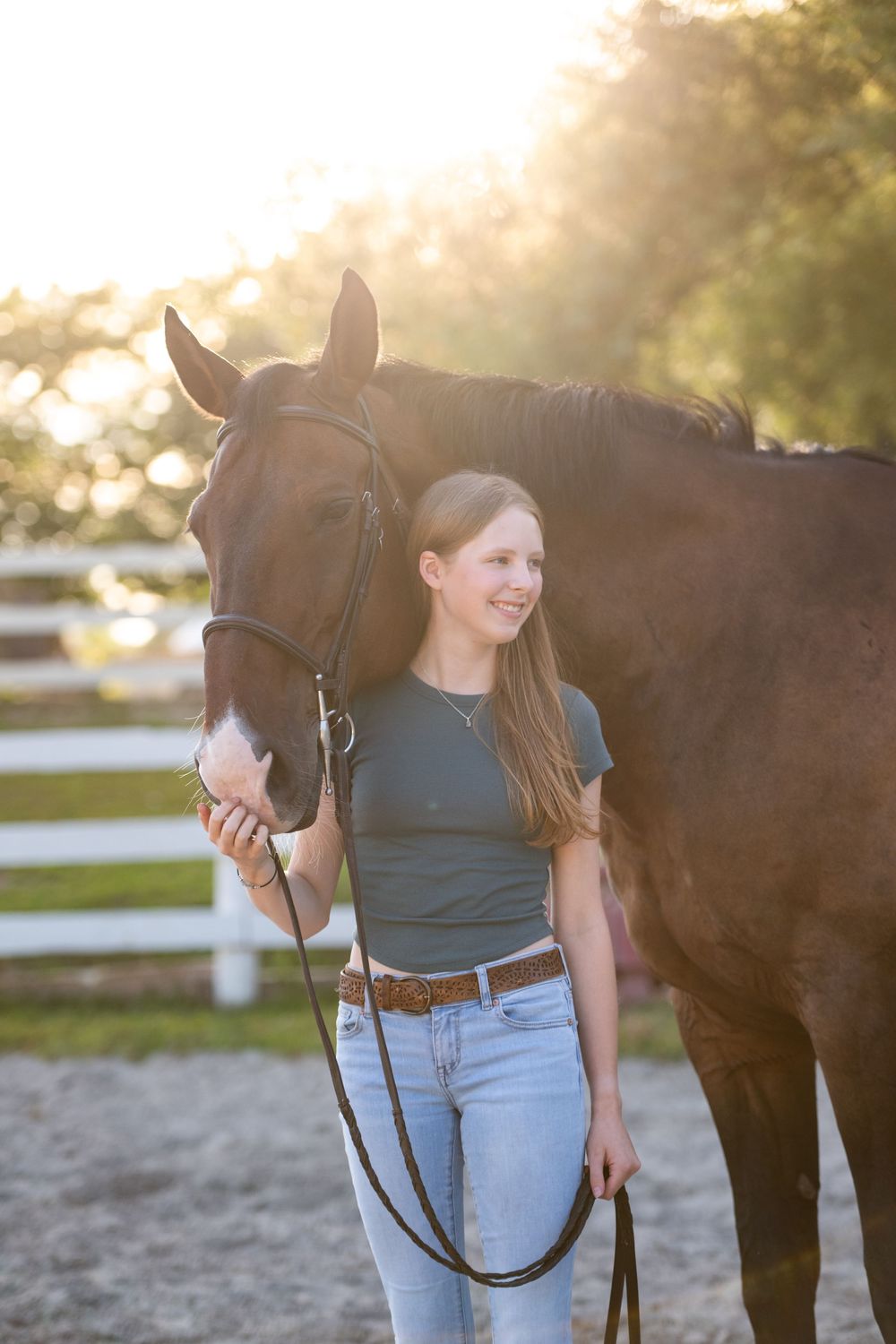 A dark bay horse and handler stand together during a golden sunset photoshoot.