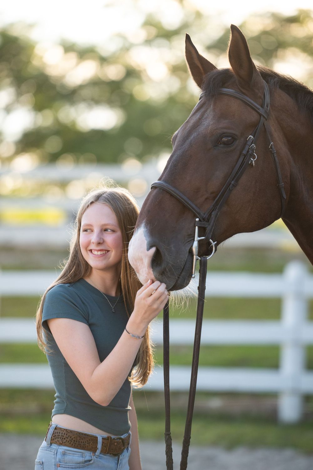 Four photos showing a young woman in a green top affectionately petting and bonding with a dark brown horse in a fenced area.