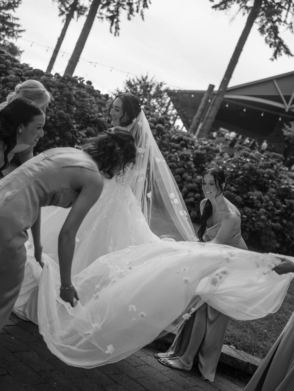 A flowing white wedding veil billows dramatically in the wind during an outdoor photoshoot.