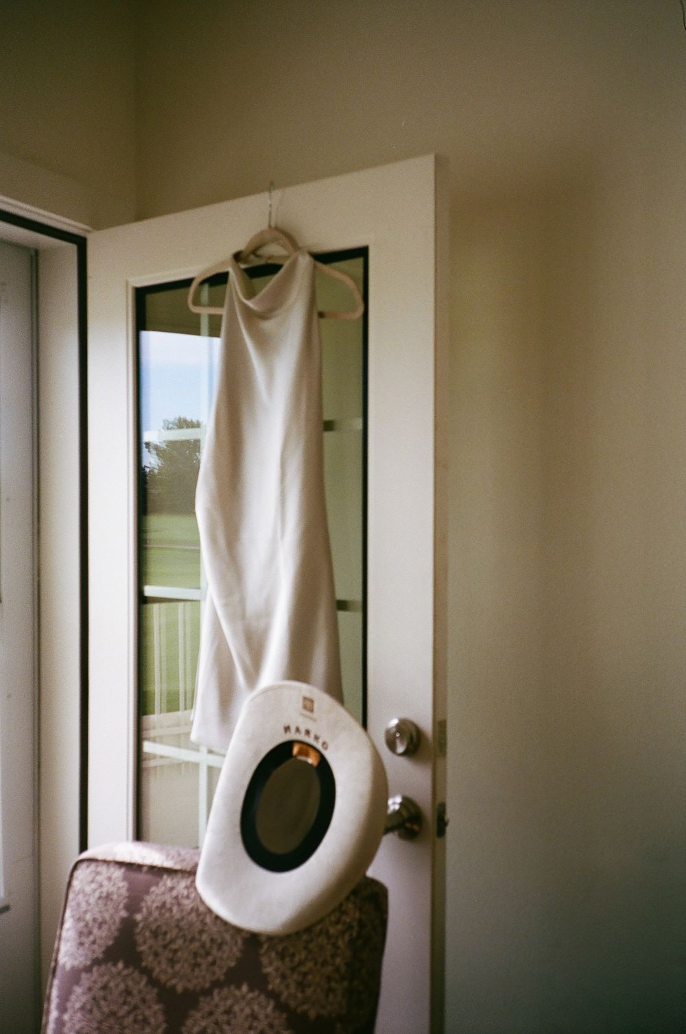 A white dress hangs mysteriously in front of a window, creating an ethereal silhouette against natural light.