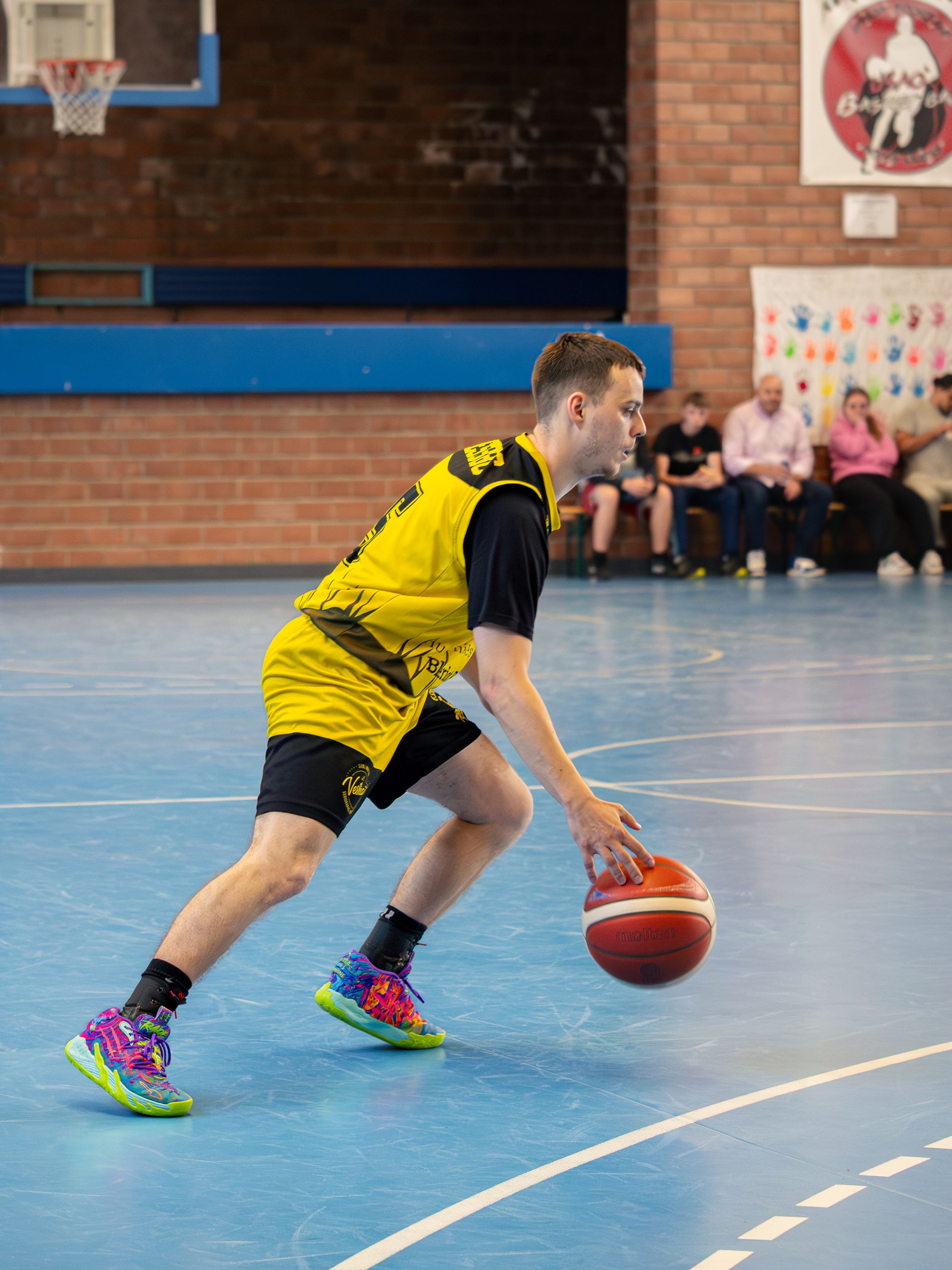 joueur de basket en tenue jaune et noir qui dribble lors d'un match de finale