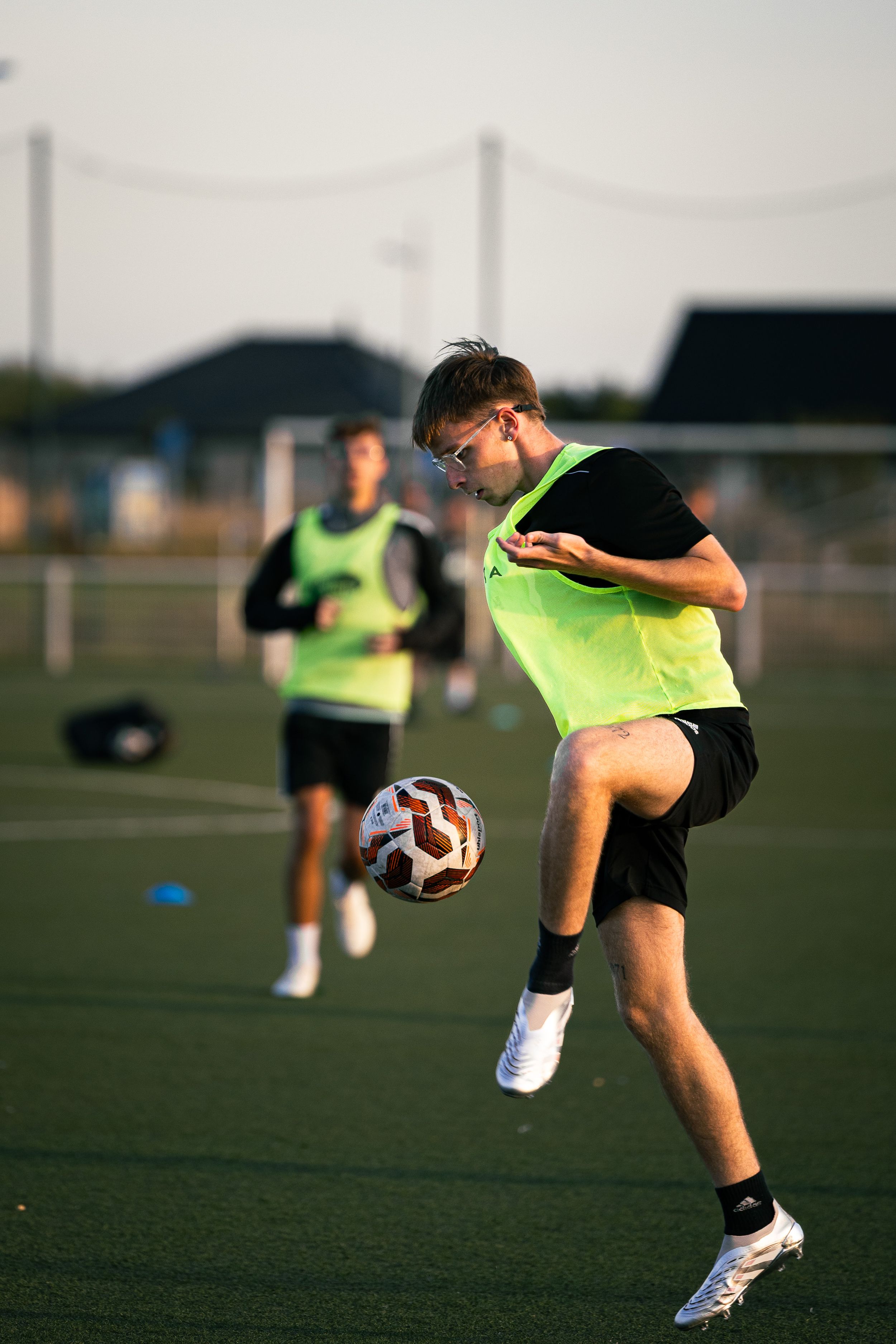 joueur de football avec un t-shirt vert qui réalise un contrôle de l'intérieur du pied gauche à la réception d'une passe