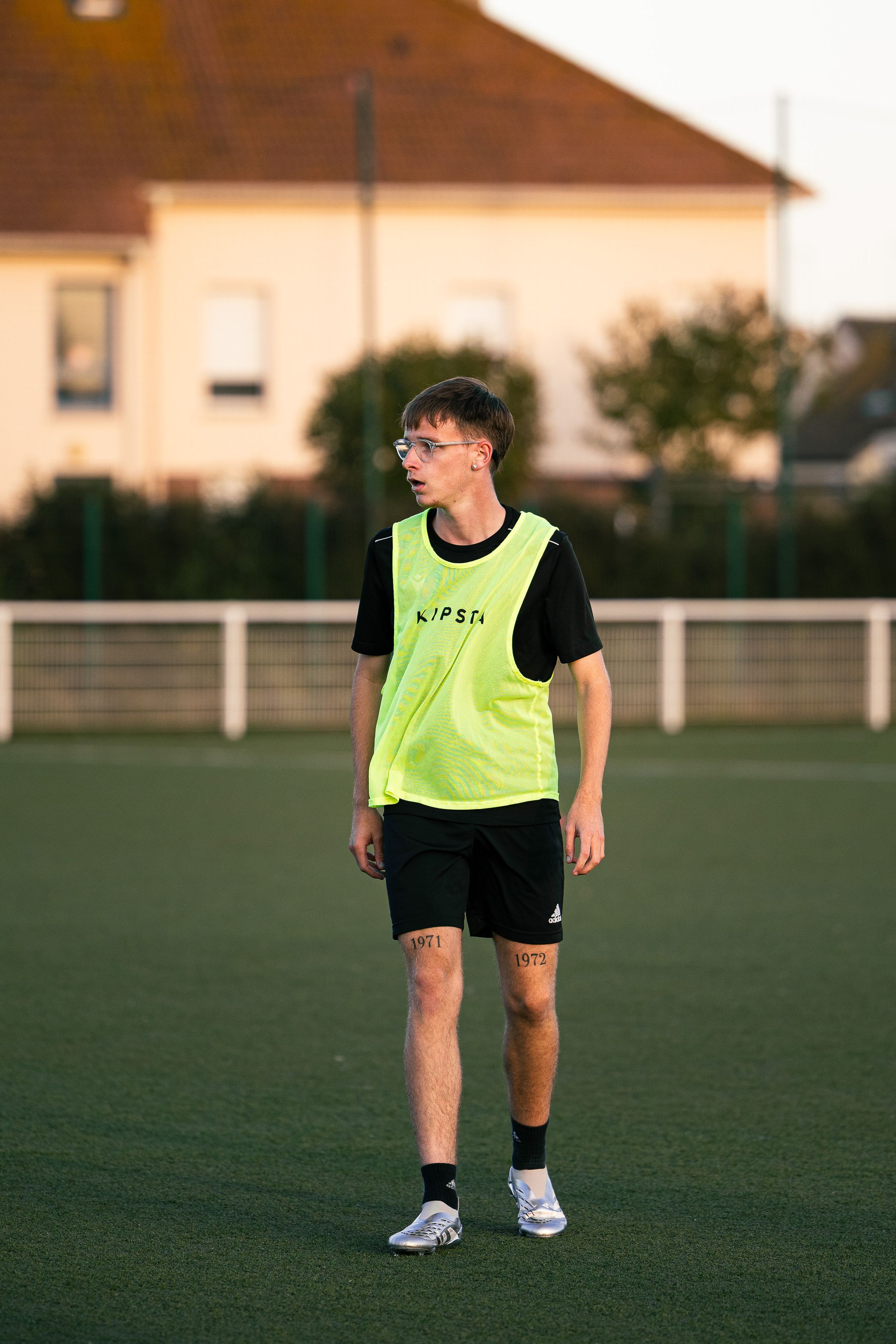 joueur de football avec un t-shirt vert qui marche sur terrain synthétique