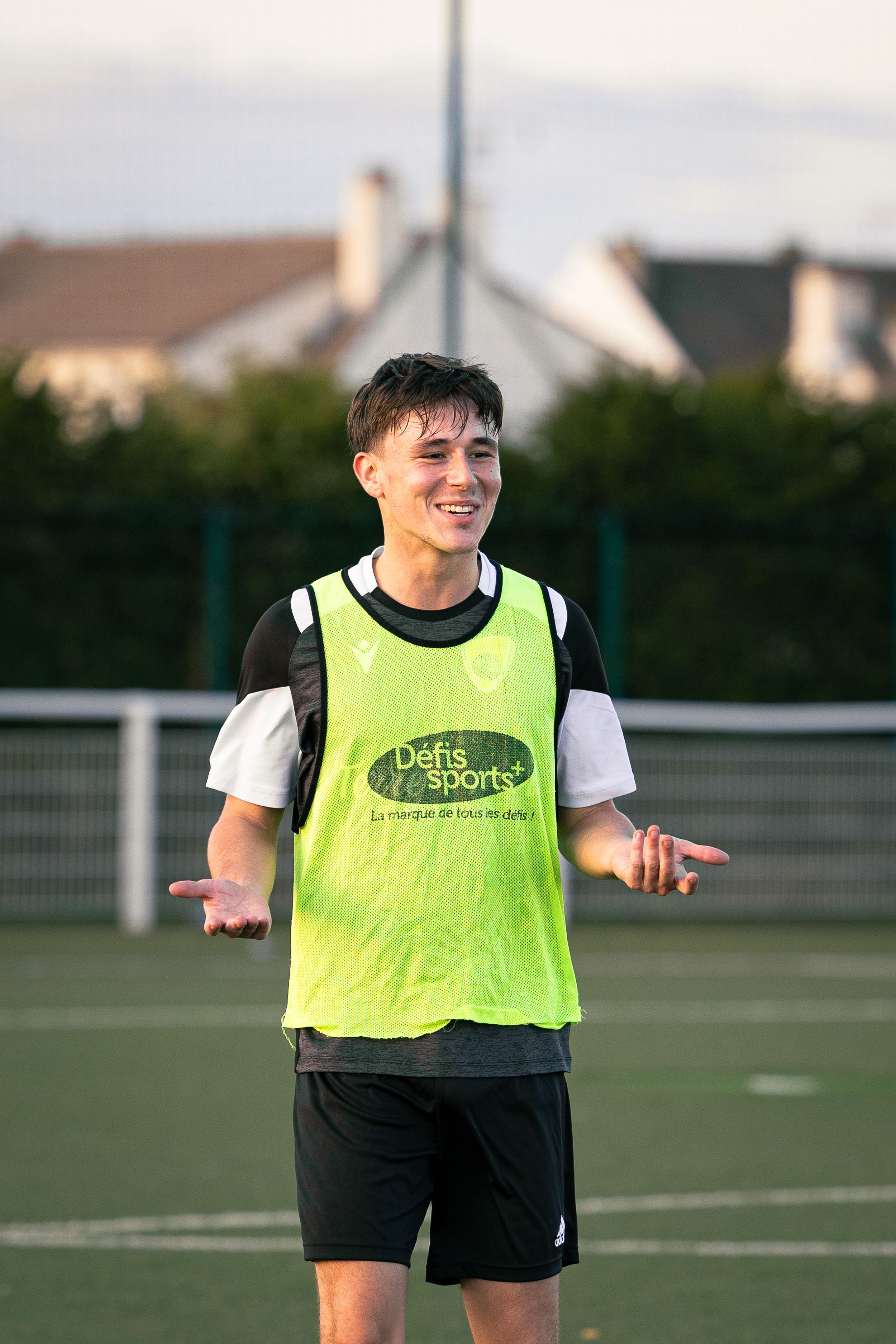joueur de football avec un t-shirt vert qui sourit lors d'un entraînement