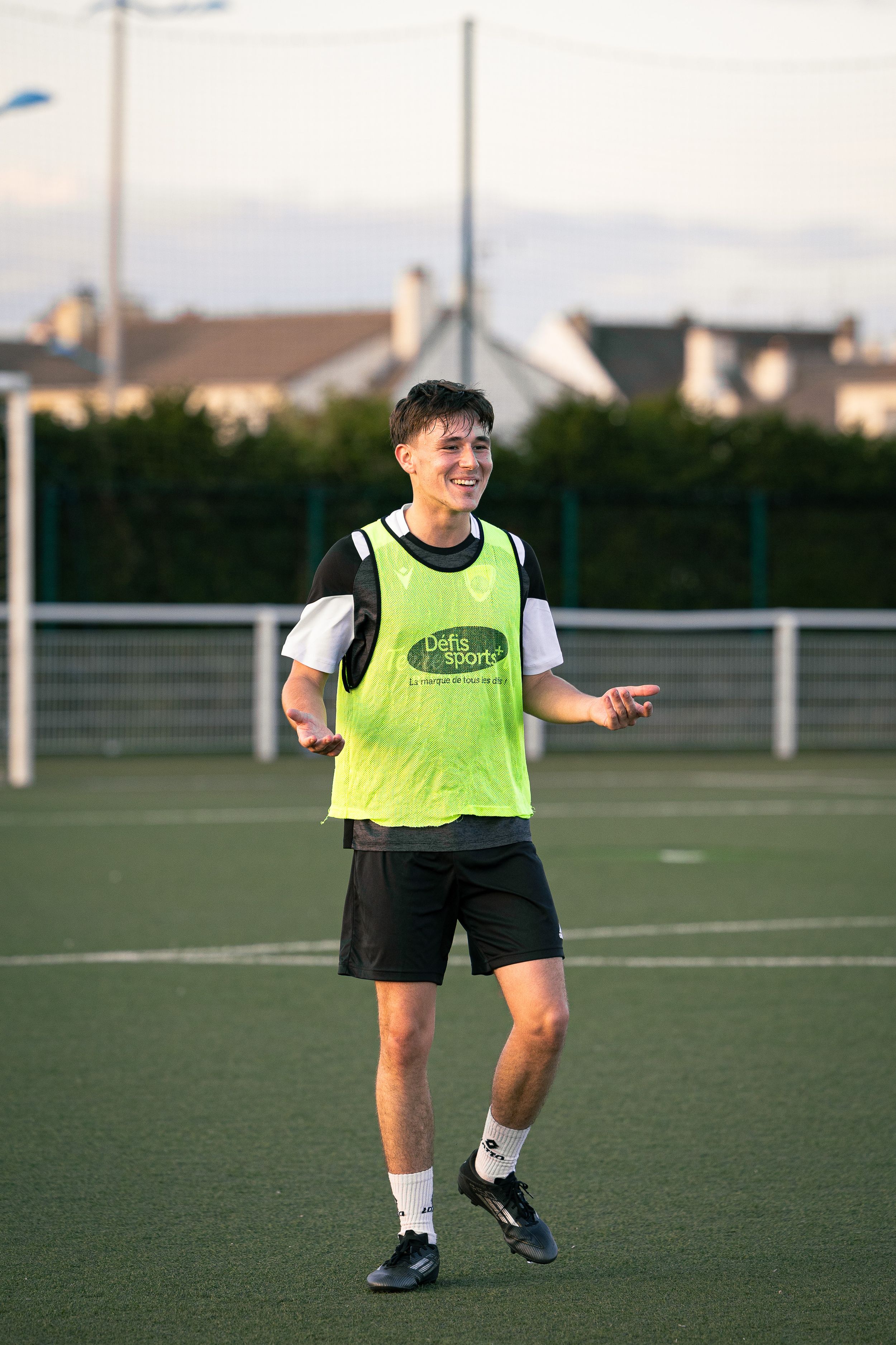 joueur de football avec un t-shirt vert qui sourit lors d'un entraînement