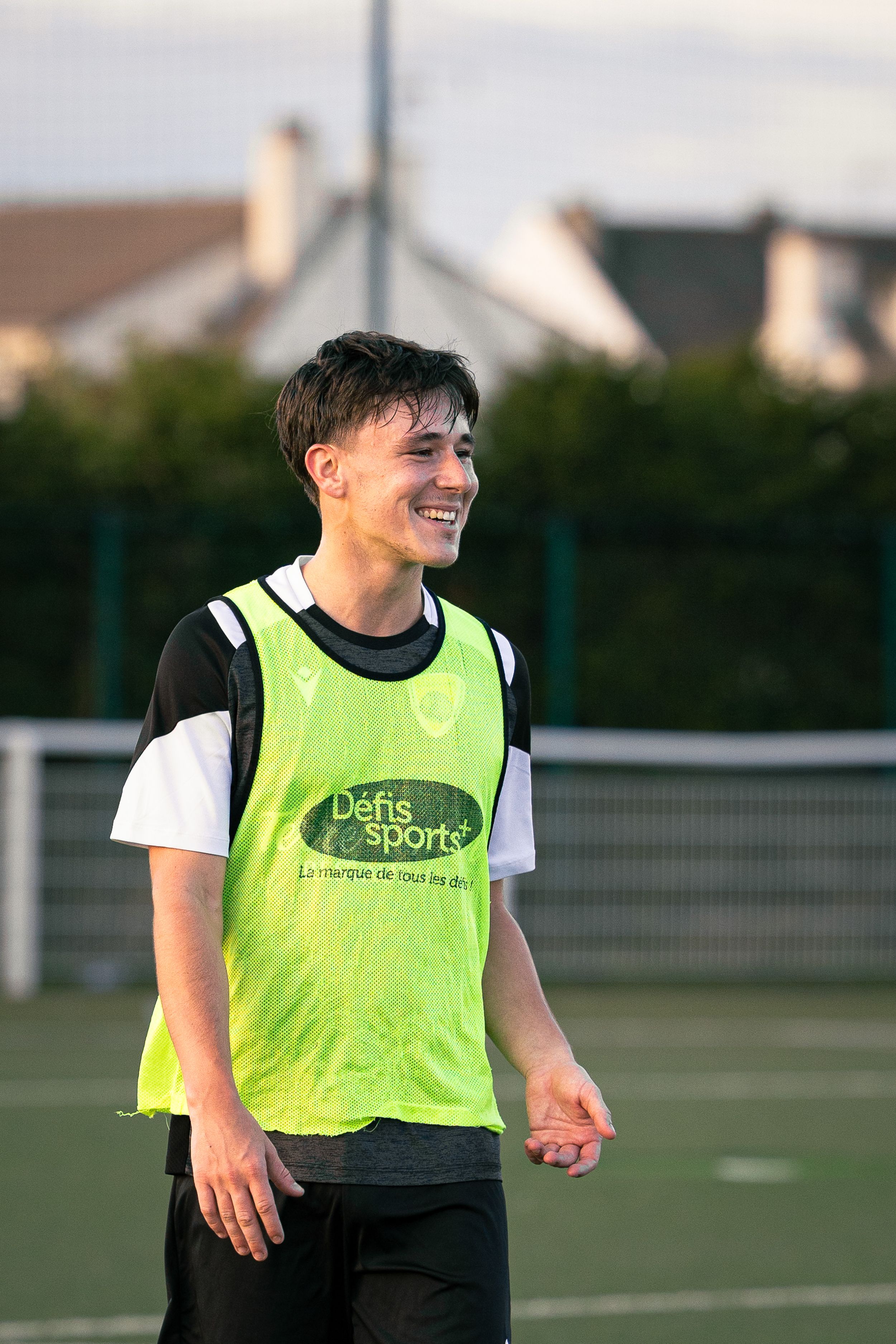 joueur de football avec un t-shirt vert qui sourit lors d'un entraînement