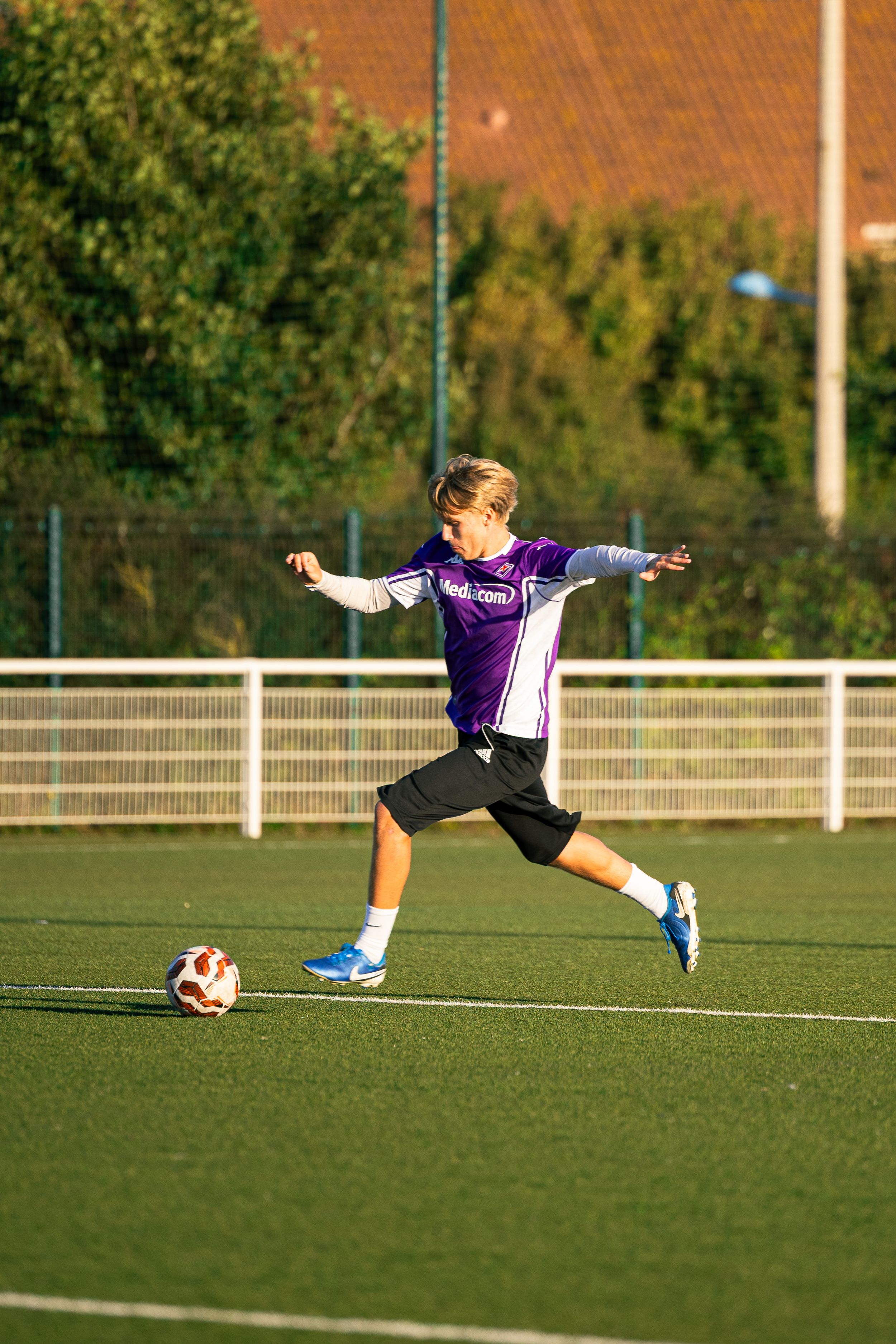 joueur de football avec haut violet qui tire au but
