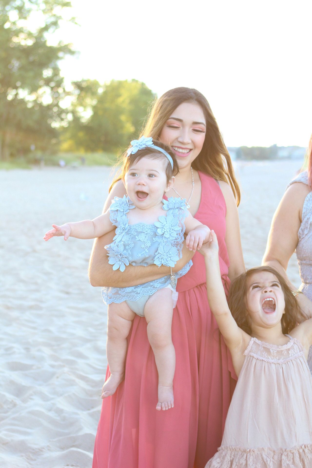 Joyful beach photoshoot with people in coordinating coral and blue outfits playing in sand.