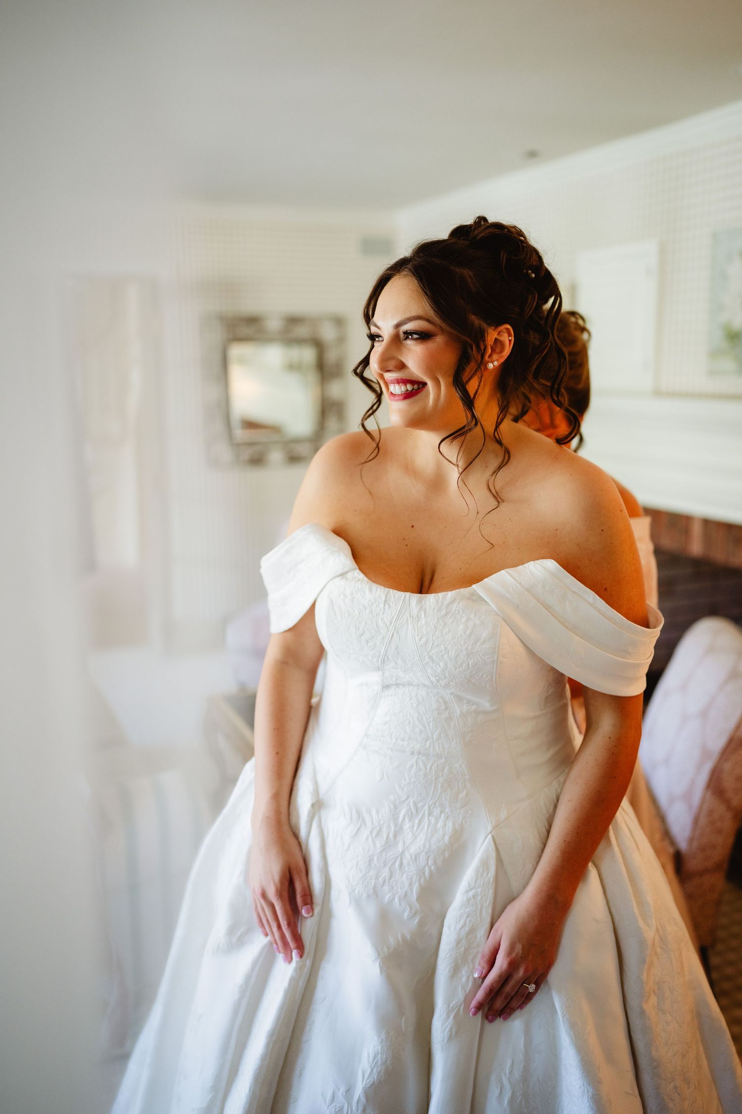 Close-up details of an elegant off-shoulder white wedding dress with intricate lace patterns and delicate embroidery.