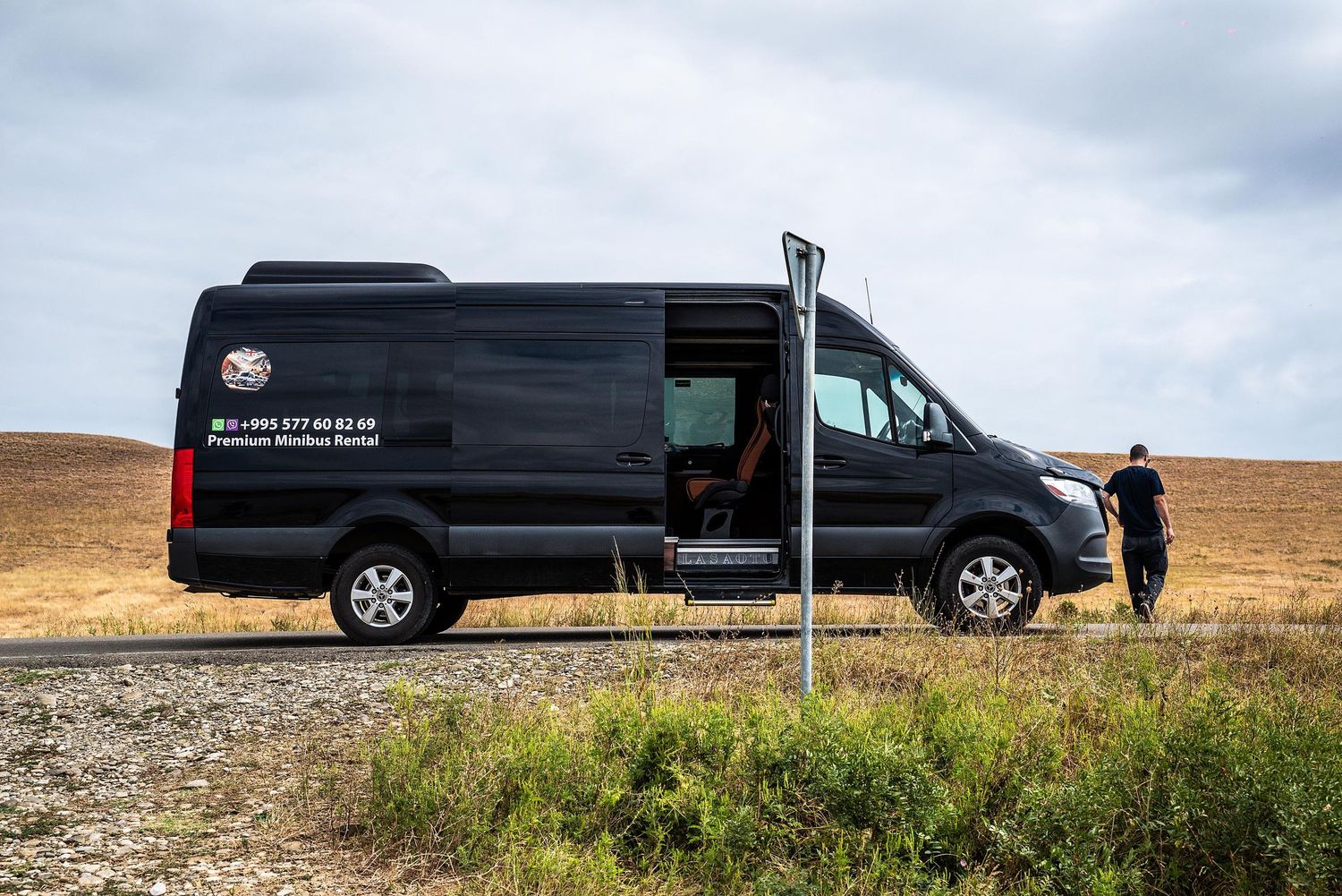 Three black vans parked in a scenic desert landscape with a cloudy sky above.