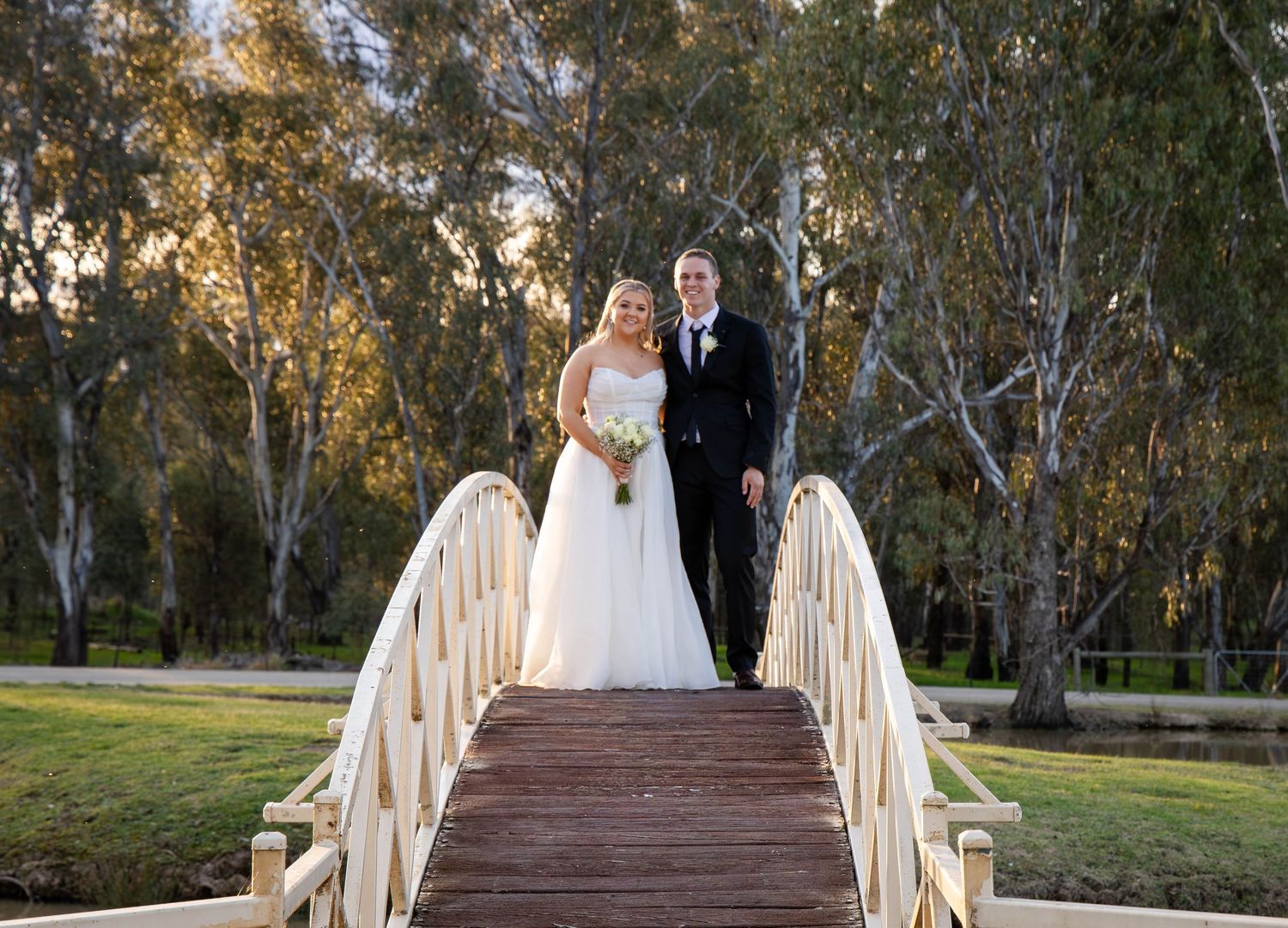 Wedding party poses for a series of elegant black and white photos outside a traditional house with white siding.