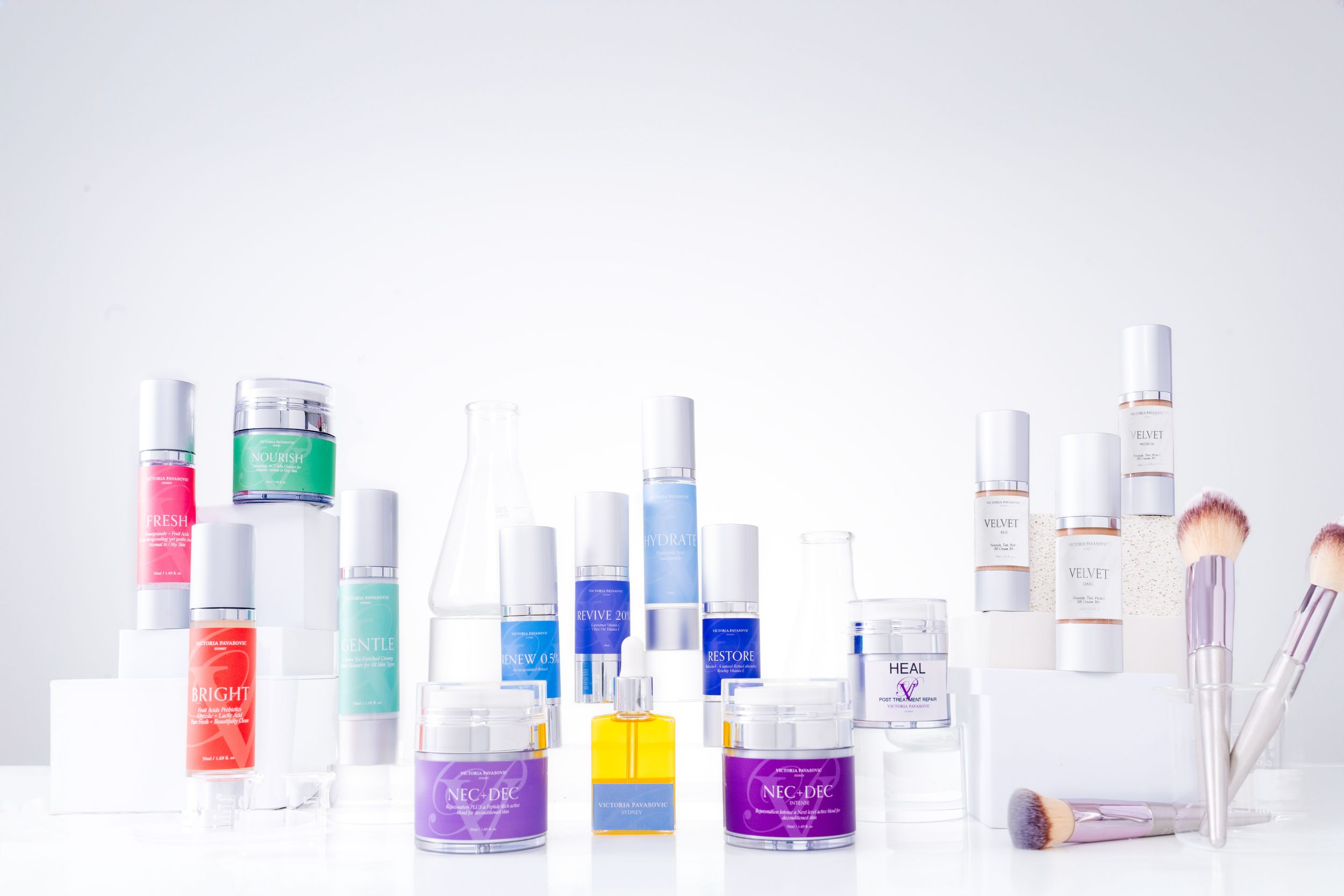 Collection of minimalist skincare product bottles and containers arranged in a clean white gradient background.