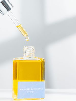 Glass dropper bottle containing golden yellow essential oil or serum against white background.