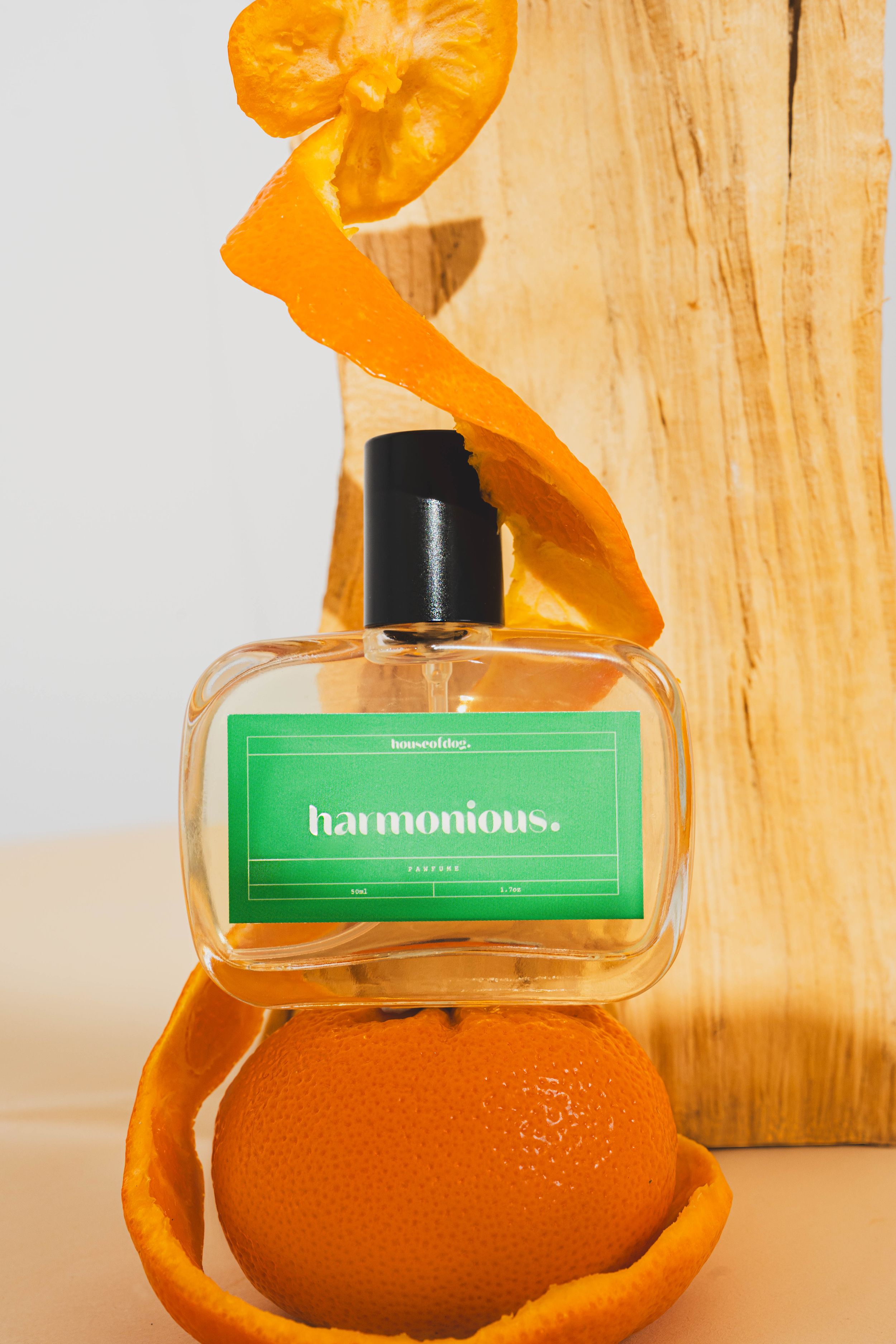A perfume bottle with a green label nestled in a curled orange citrus peel against a wooden background.