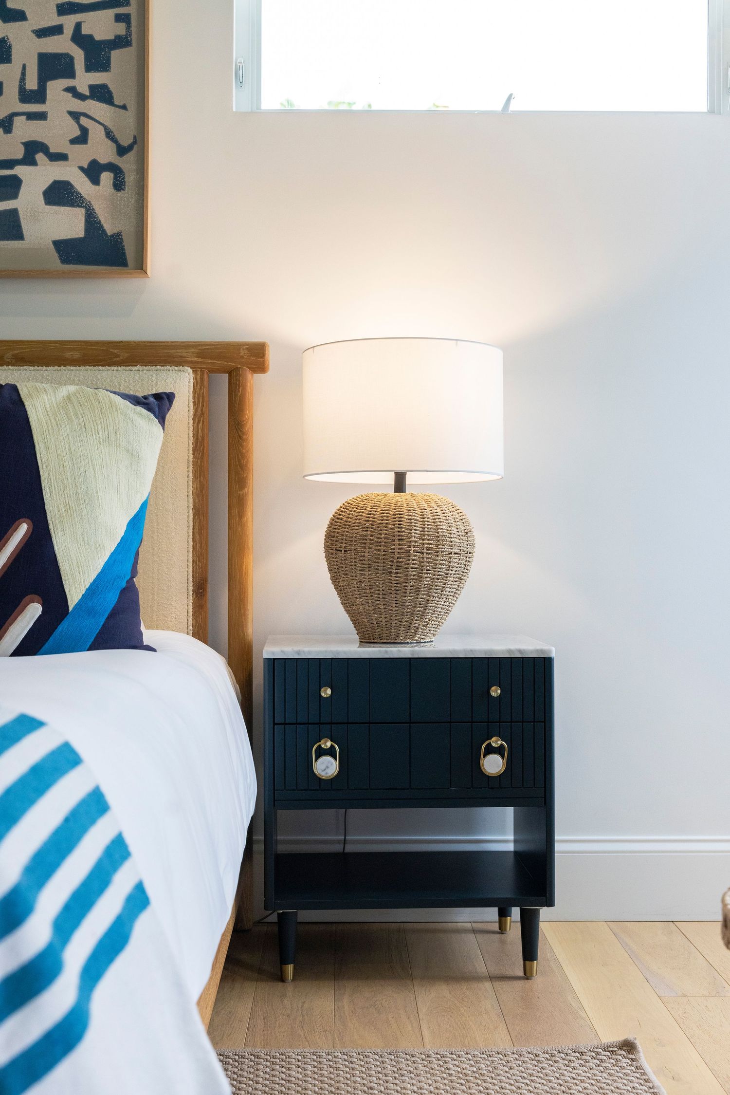 Modern bedroom decor featuring a black nightstand with textured lamp and blue accent pillows.