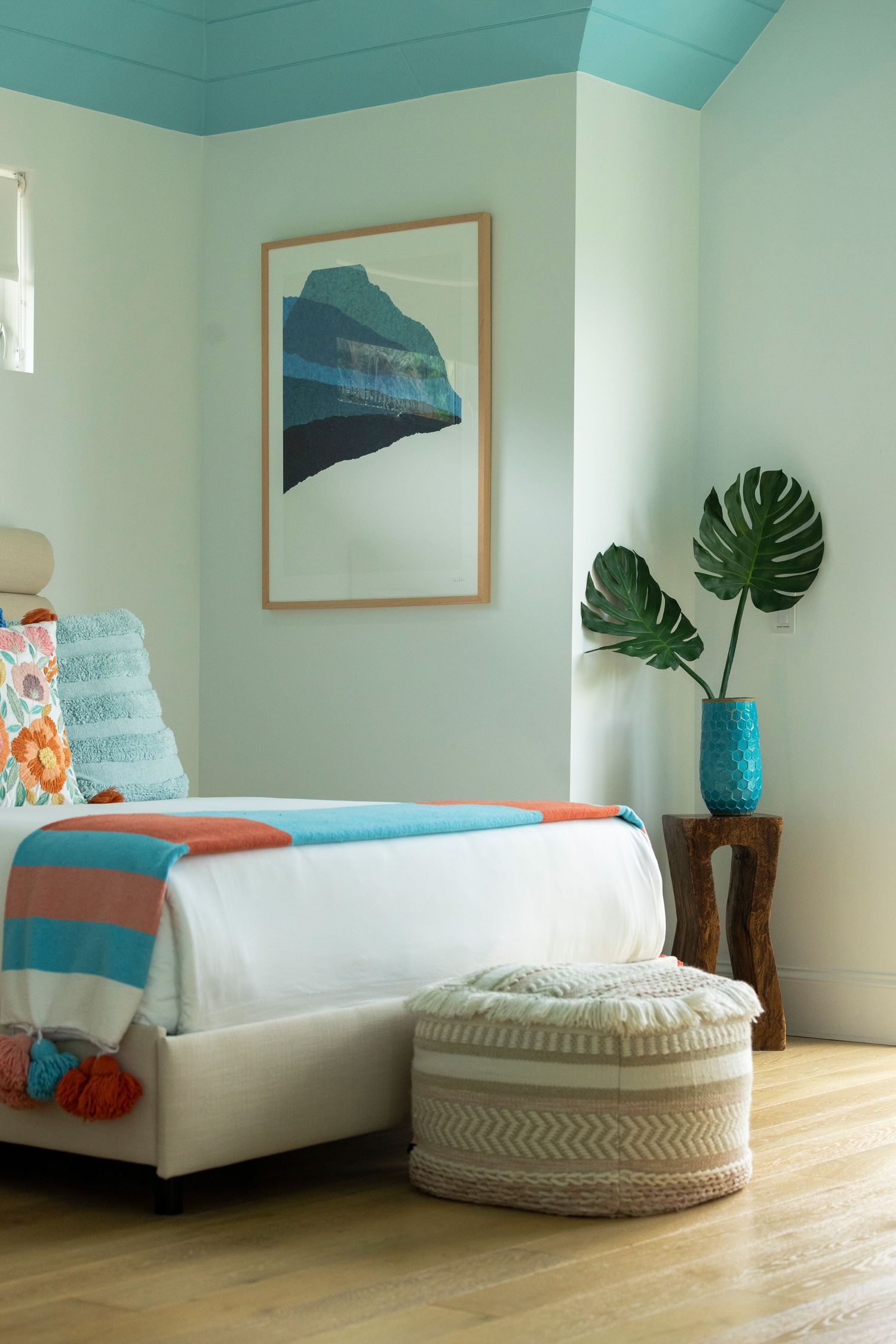 Serene bedroom with mint green walls, tropical plants, and coastal-inspired decor elements.