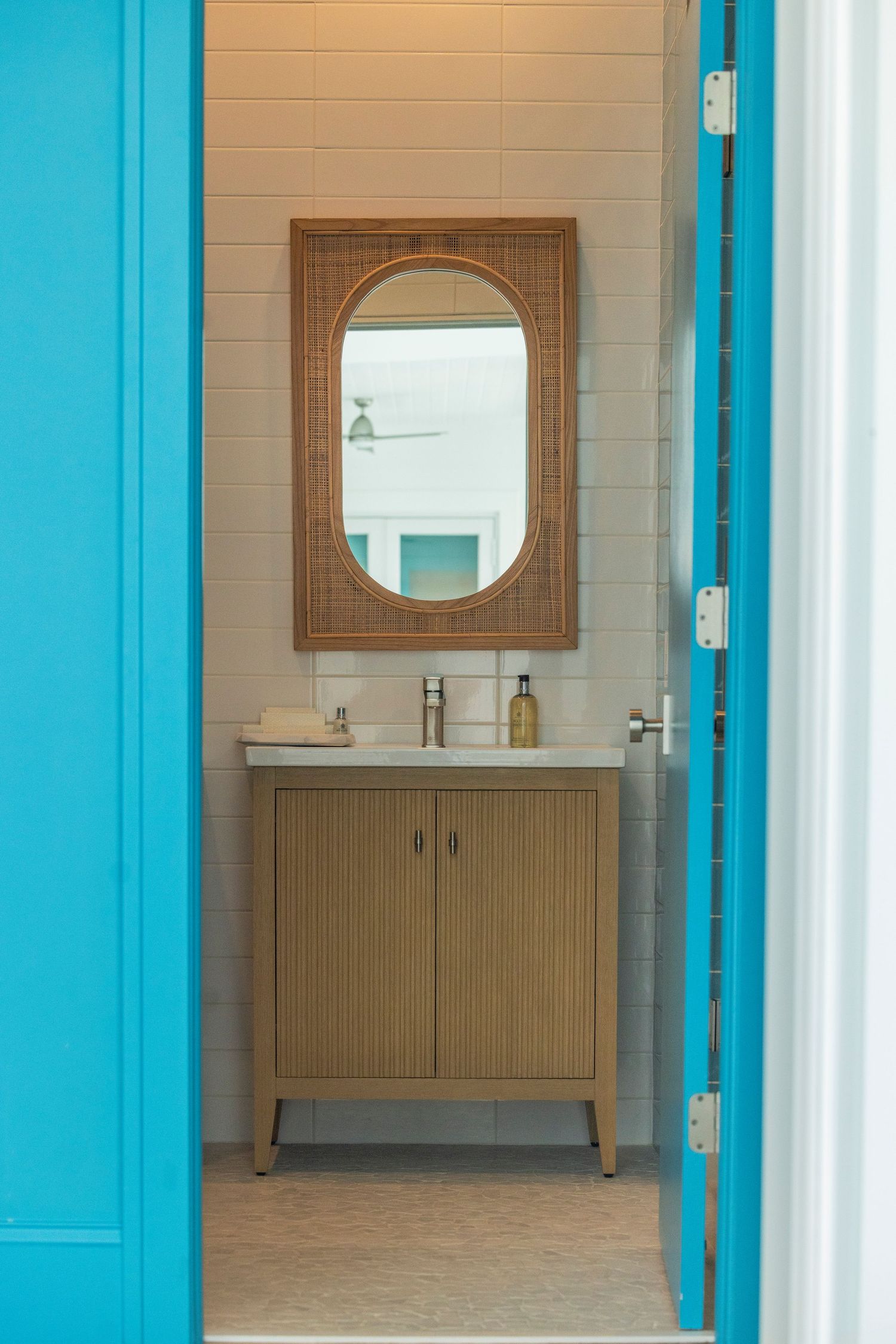 Bathroom entrance with turquoise door frame and wooden vanity cabinet inside.