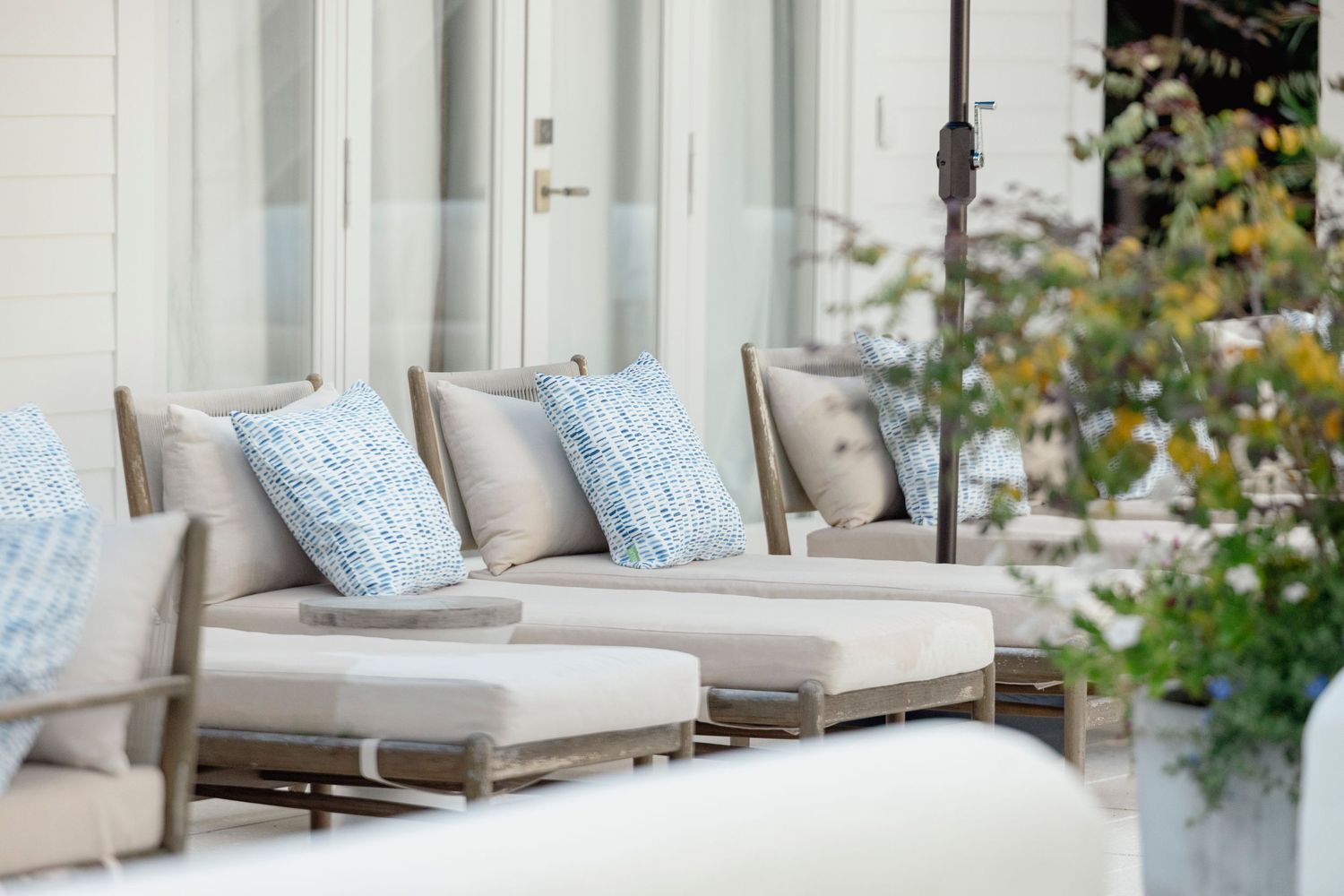 Elegant outdoor seating area with white cushioned chairs and coastal decor.