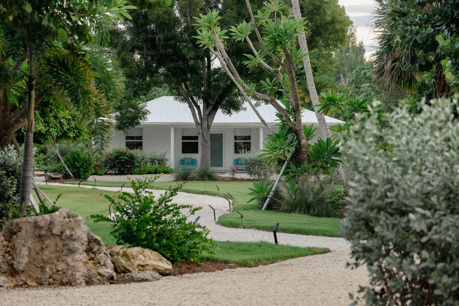 Lush garden landscaping with mature trees, shrubs and winding pathway bordered by well-maintained greenery.