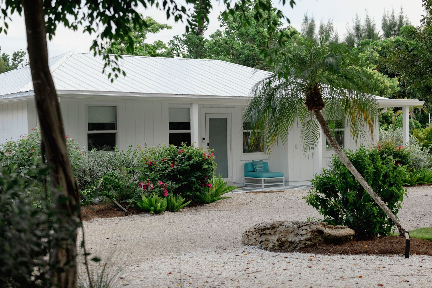 White coastal property with palm trees and shell driveway leading to entrance.