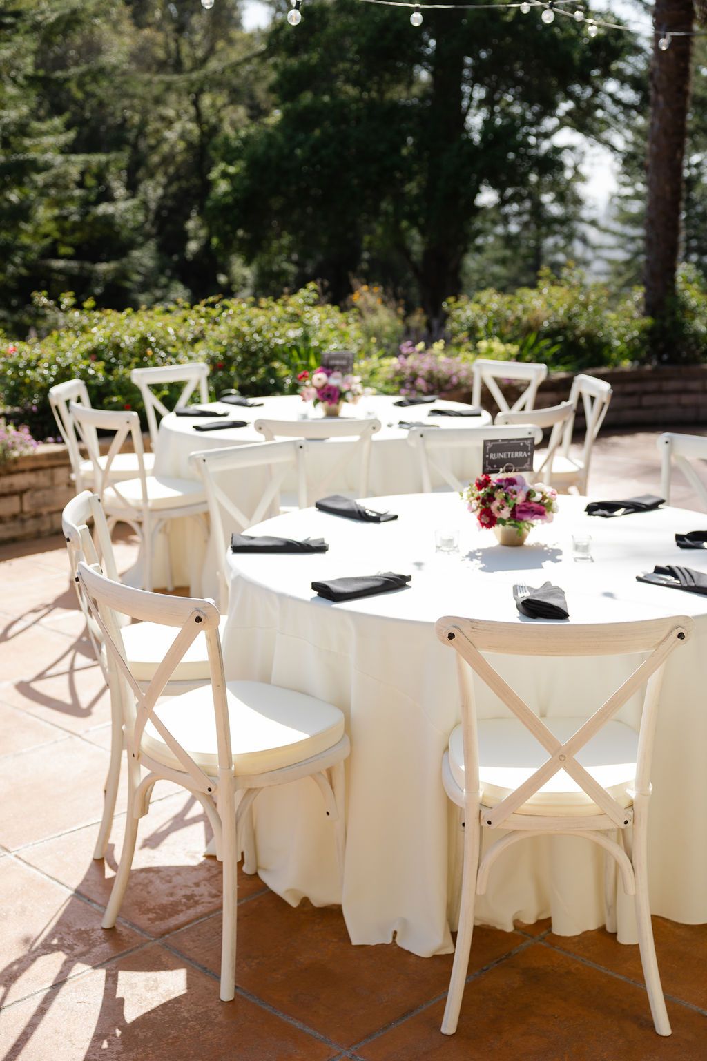Table settings with pink and burgundy floral centerpieces arranged in curved golden bowls with white place cards.