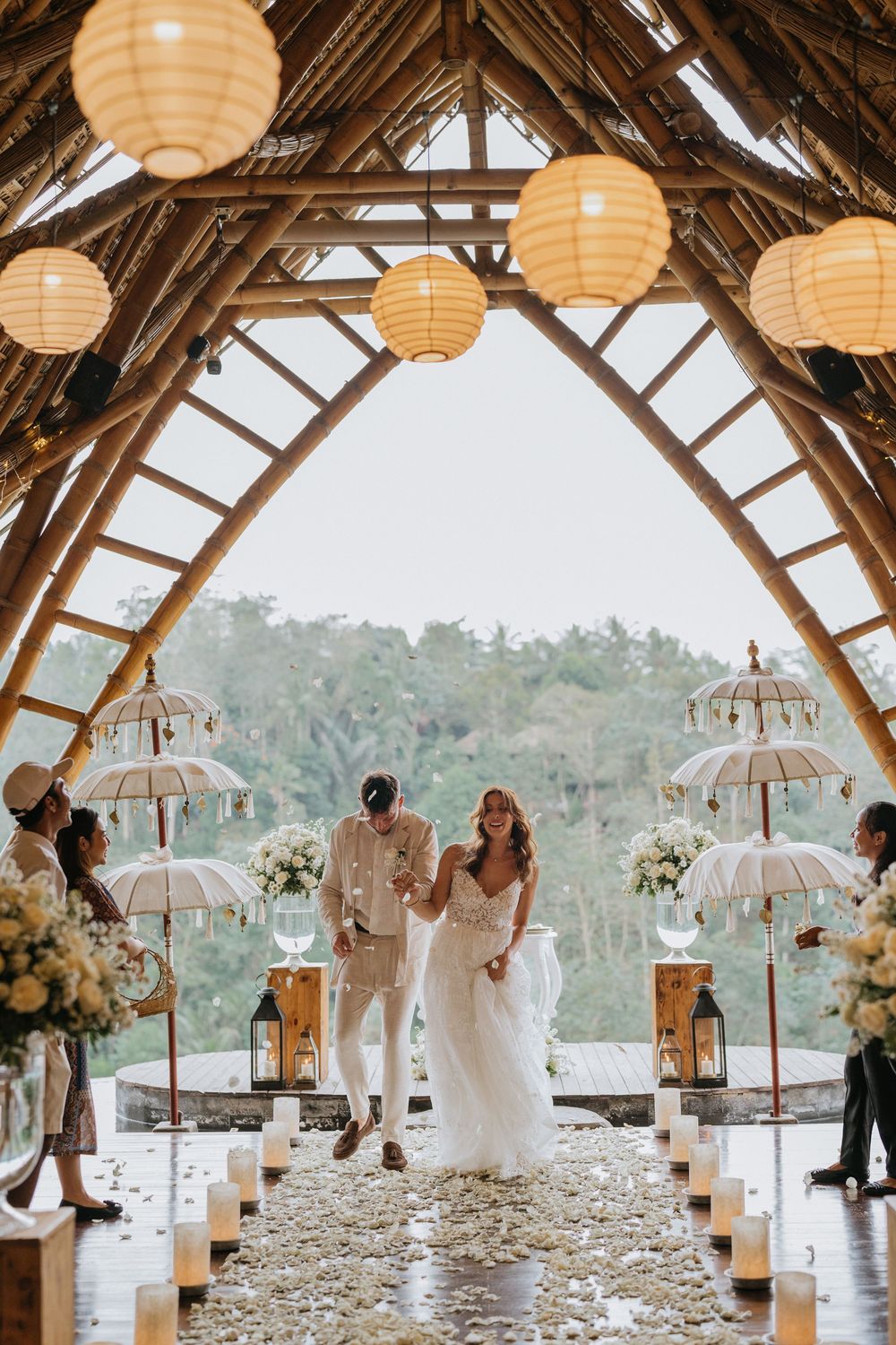 A tropical wedding venue decorated with hanging lanterns and white parasols creating a dreamy atmosphere.