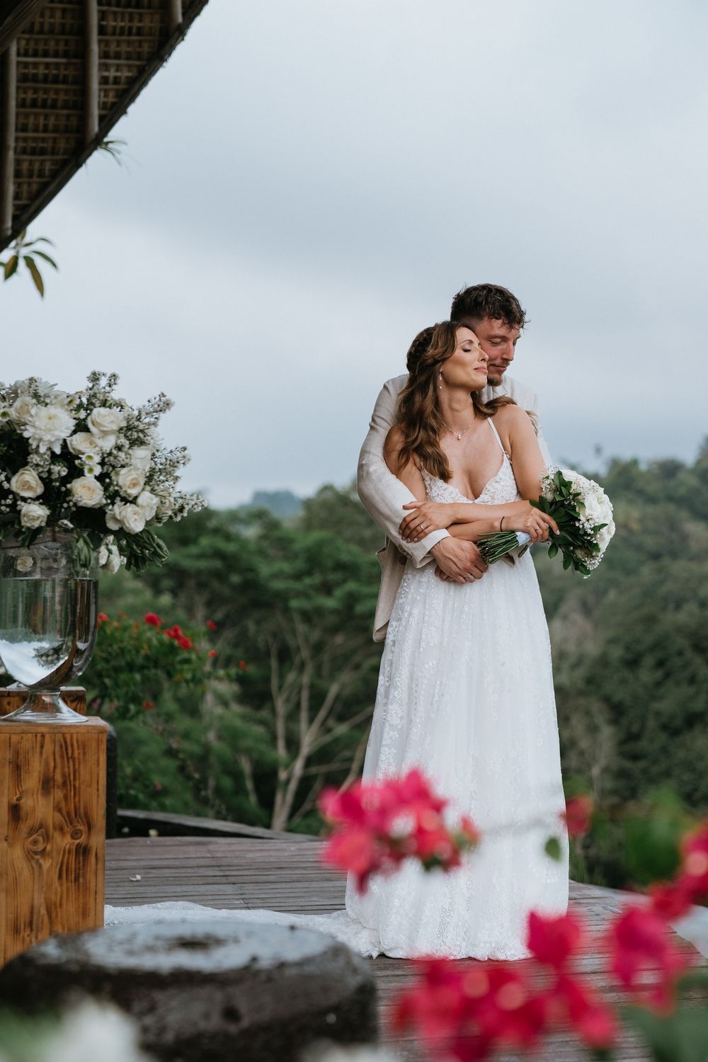 A romantic wedding moment captured on a deck with pink bougainvillea flowers in the foreground.