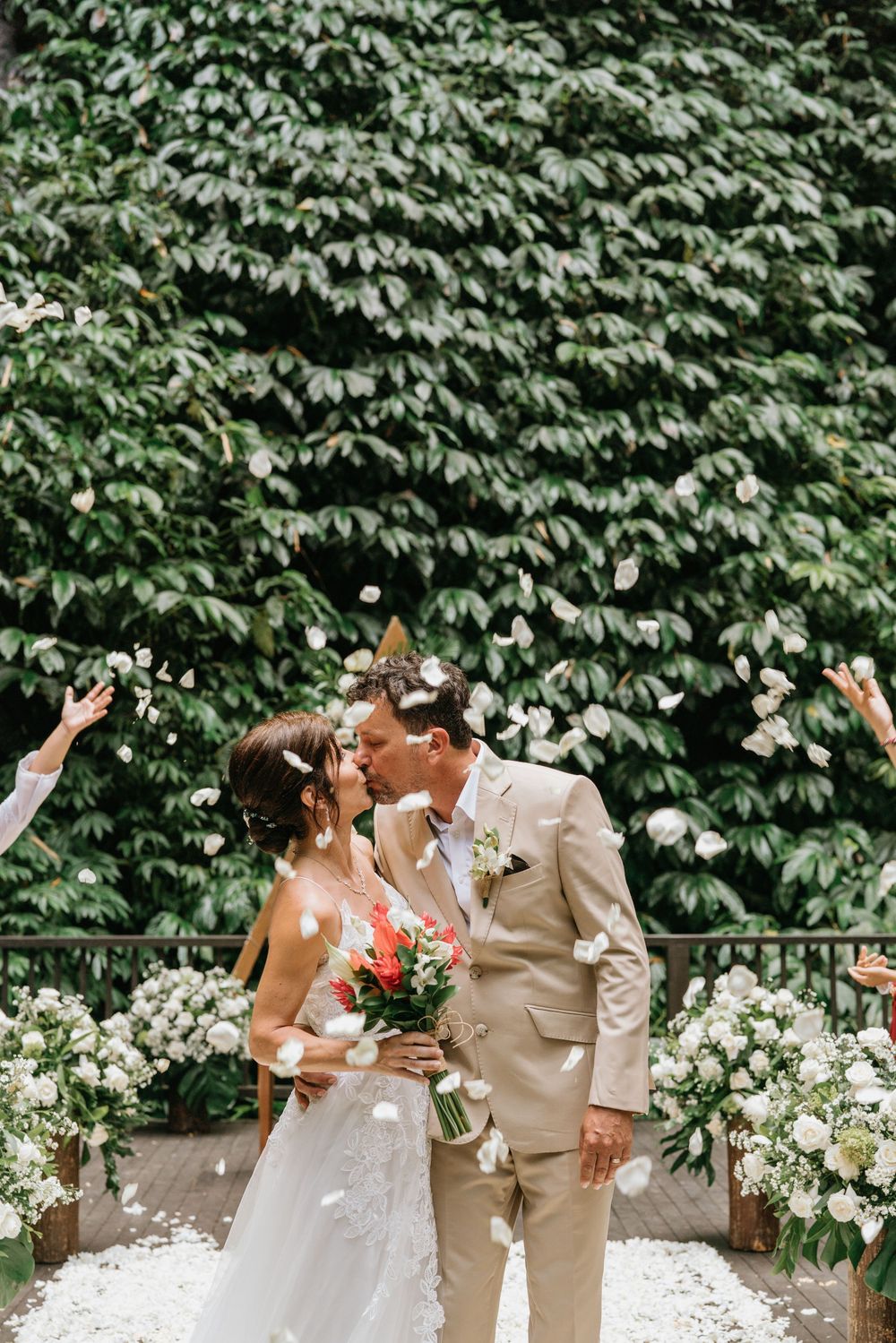 A joyful wedding celebration moment on a deck decorated with white flowers and green foliage.