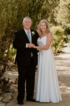 Wedding couple poses outdoors in a natural setting with dappled sunlight filtering through trees for romantic photos.