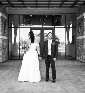 Black and white wedding sequence showing a couple stepping apart in a covered outdoor venue with stone pillars.