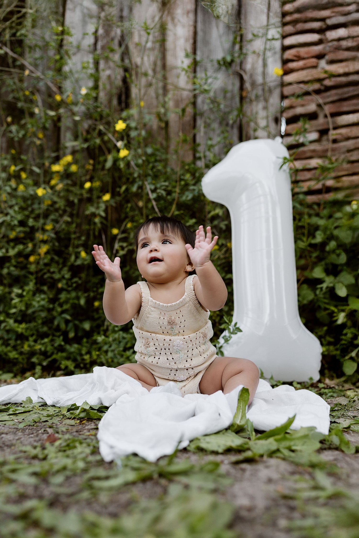 A set of four sequential photos showing a baby wearing a knit dress on grass near white textured walls.