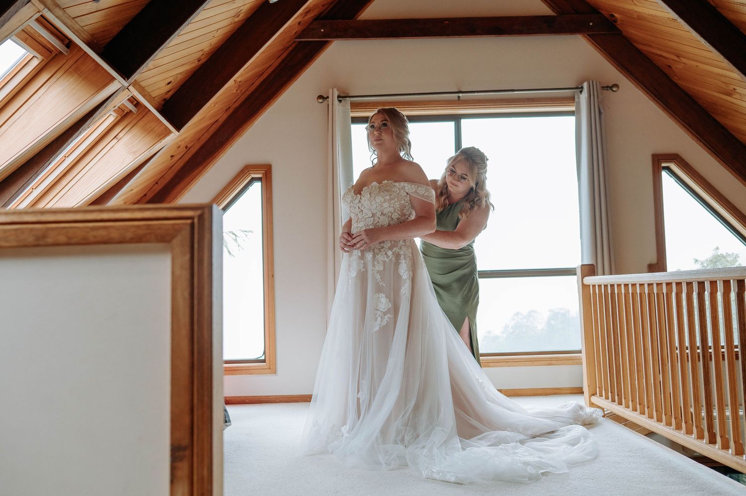 A wedding dress preparation moment in a rustic attic space with wooden beams and natural light.