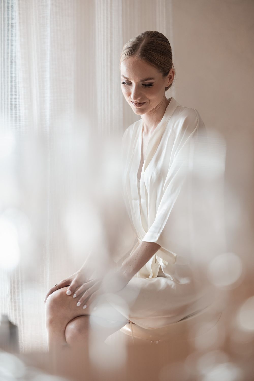 Soft and dreamy bridal morning preparation scene with white curtains and gentle natural light.