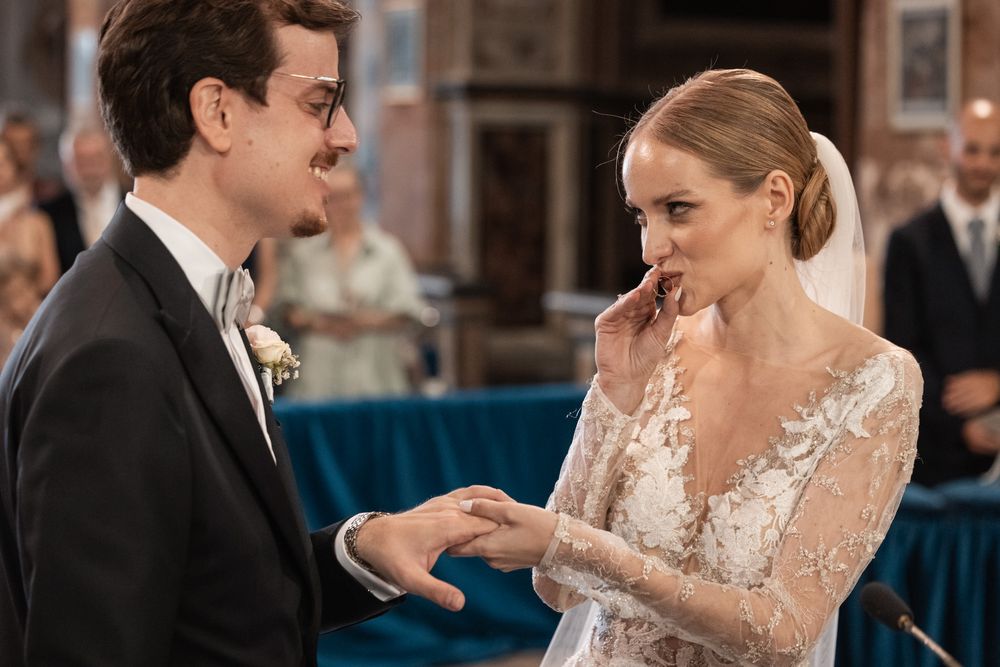 Intimate moment during wedding ceremony exchange of rings in church setting.