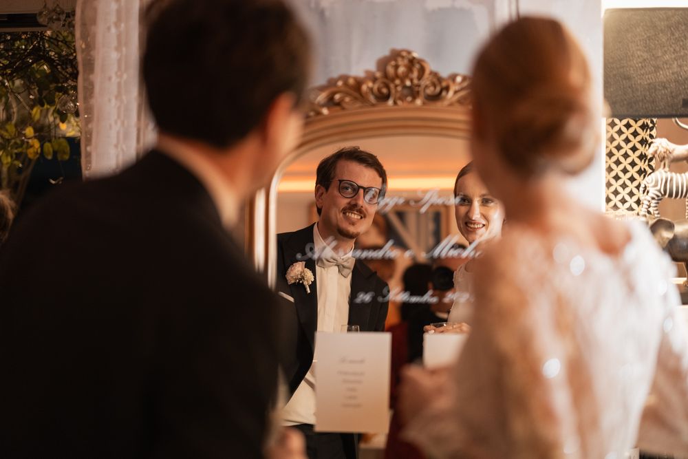 Wedding ceremony in an elegant room with ornate mirror and decorative details.
