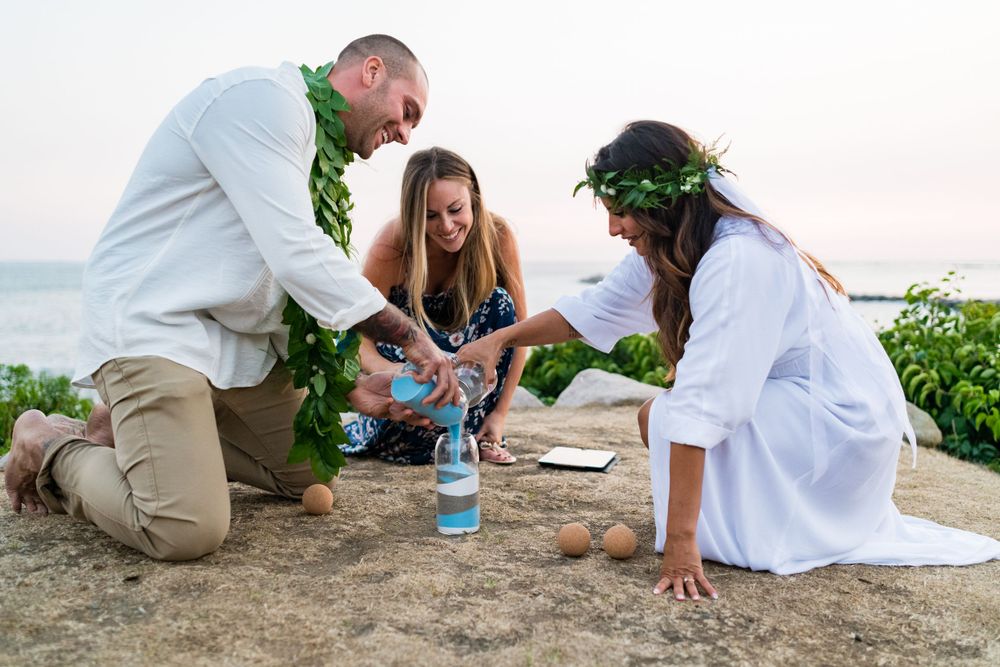 Family participates in a traditional Hawaiian sand ceremony during an intimate beach wedding celebration.