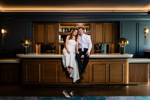 Bride and groom sit together at elegant hotel bar with gold accents.