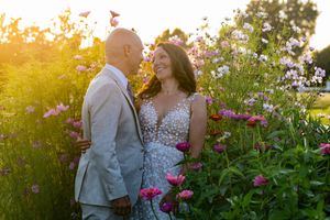 Joyful couple sharing a romantic moment surrounded by colorful blooming flowers at sunset.