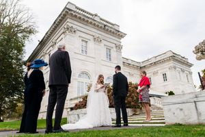 Intimate small wedding ceremony on steps of grand white historic mansion with family witnesses.