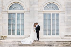 Bride and groom sharing a romantic moment on marble steps of a grand estate building.
