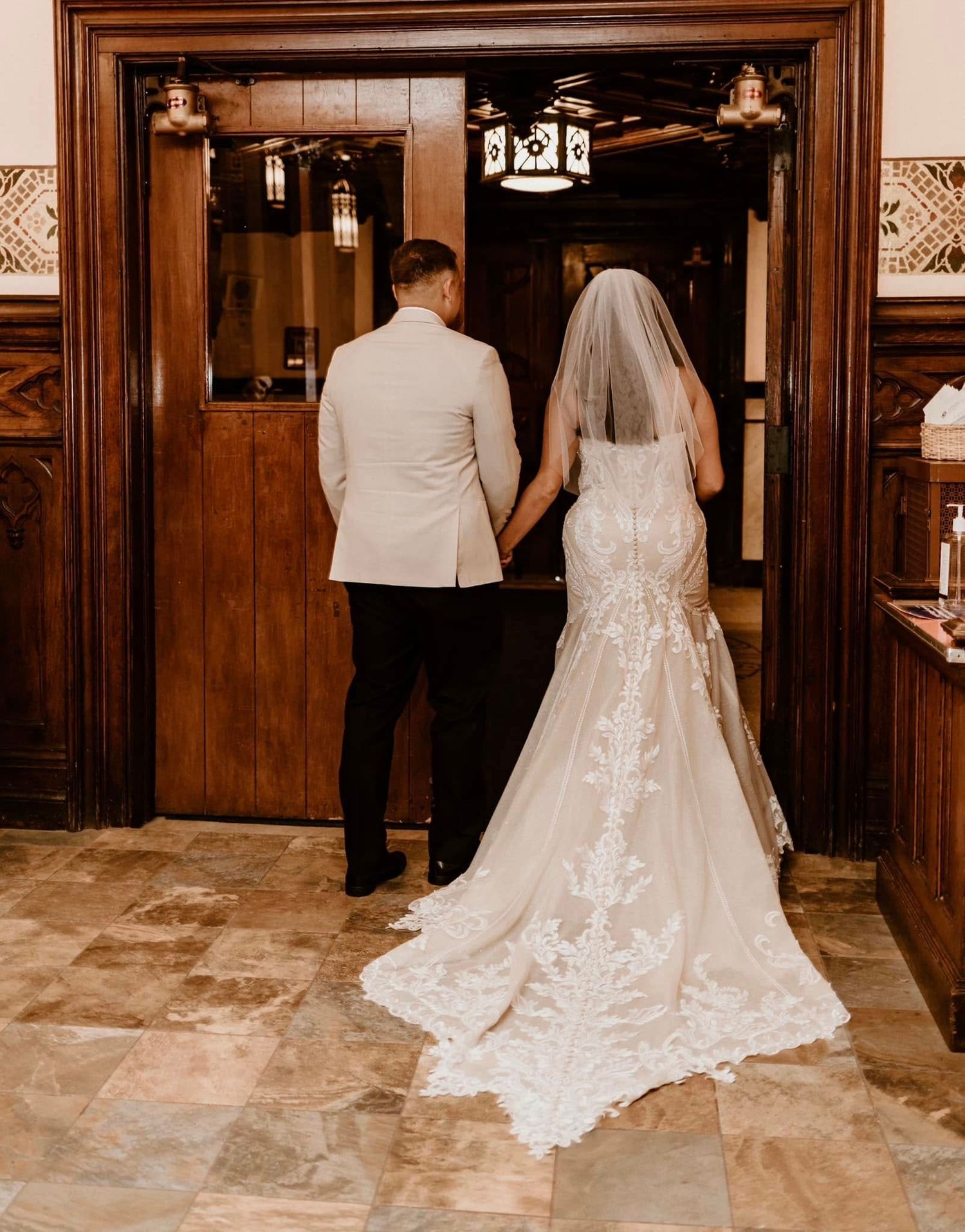 A couple share an intimate moment during their wedding ceremony in an ornate cathedral with stained glass windows.