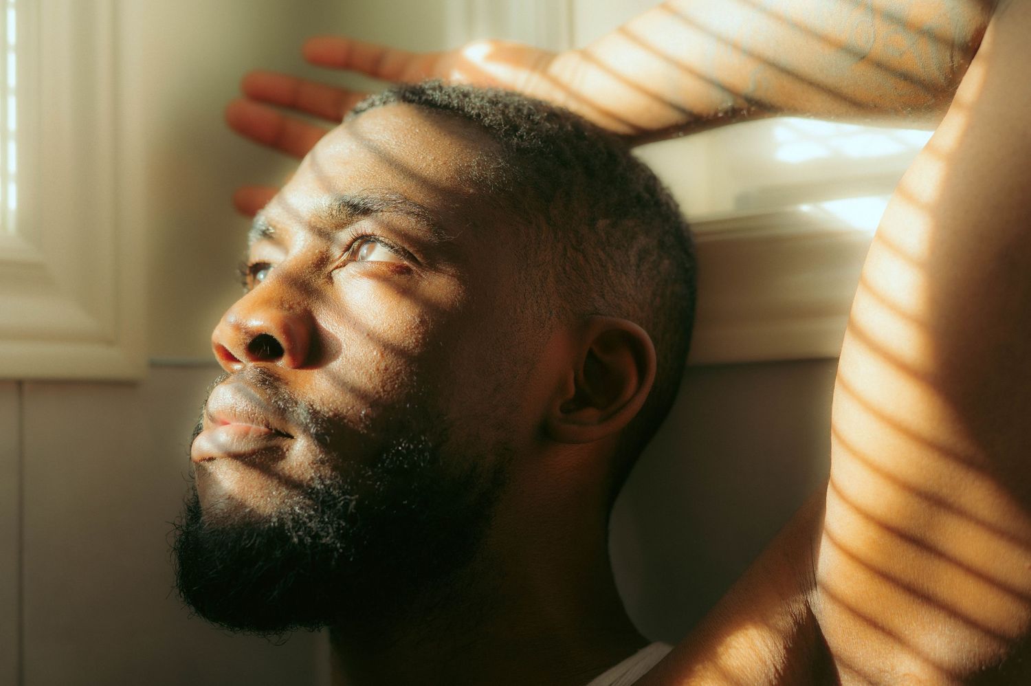 Artistic portrait with dramatic window lighting and venetian blind shadows.