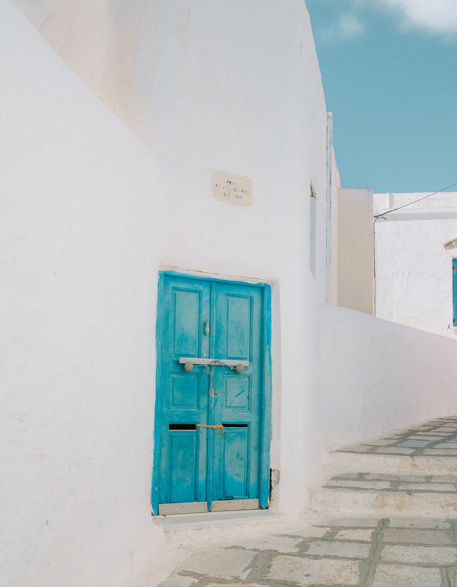 Minimal Aegean-style facade with bright blue shutters and door.