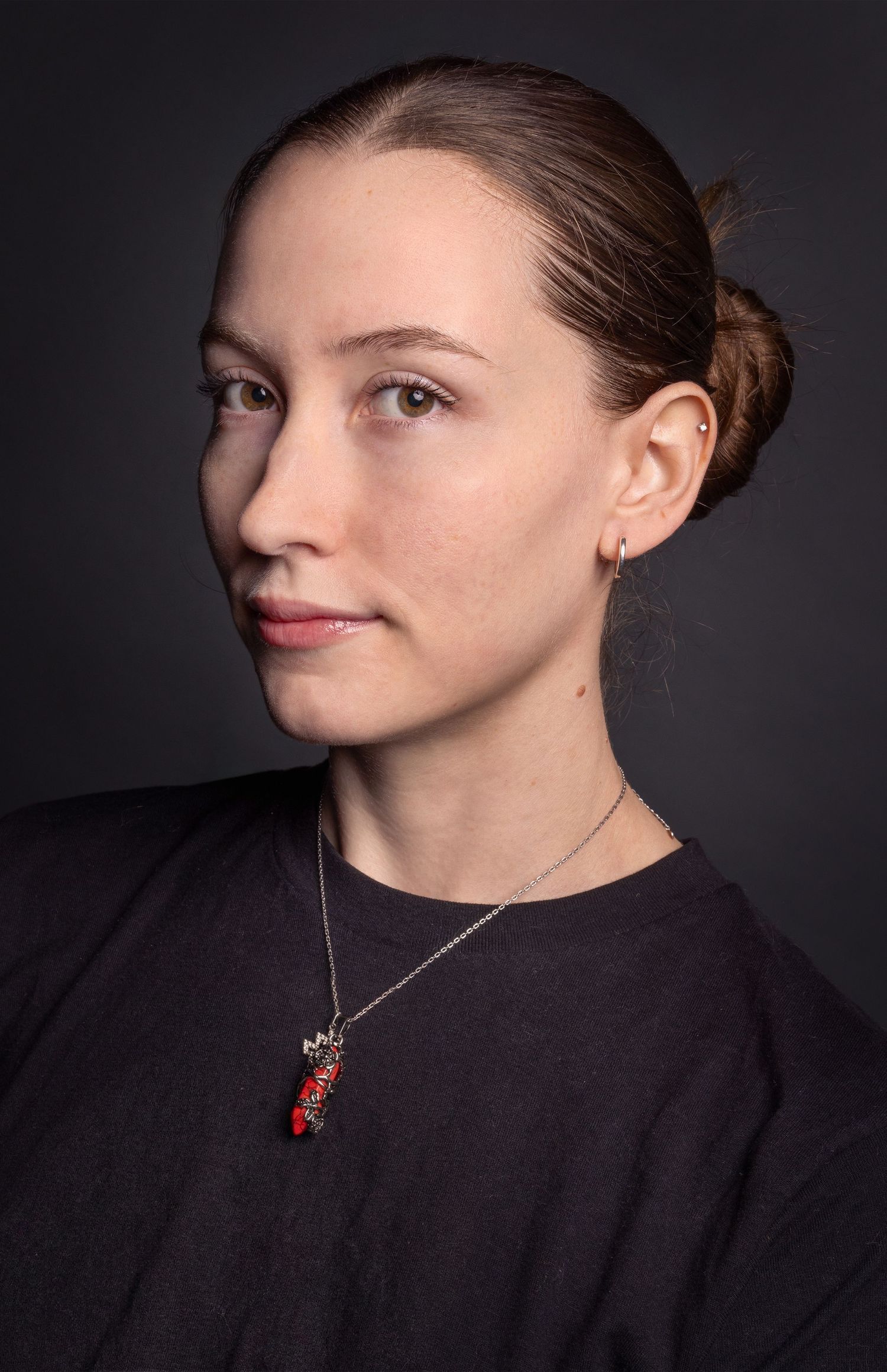 Close-up studio portrait of a woman looking to the side against a dark background.