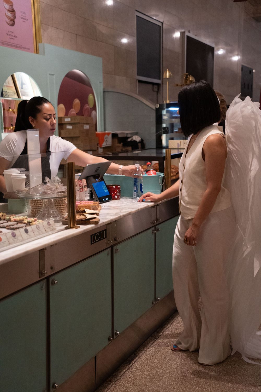 Customer in angel wings costume ordering at a casual food counter.